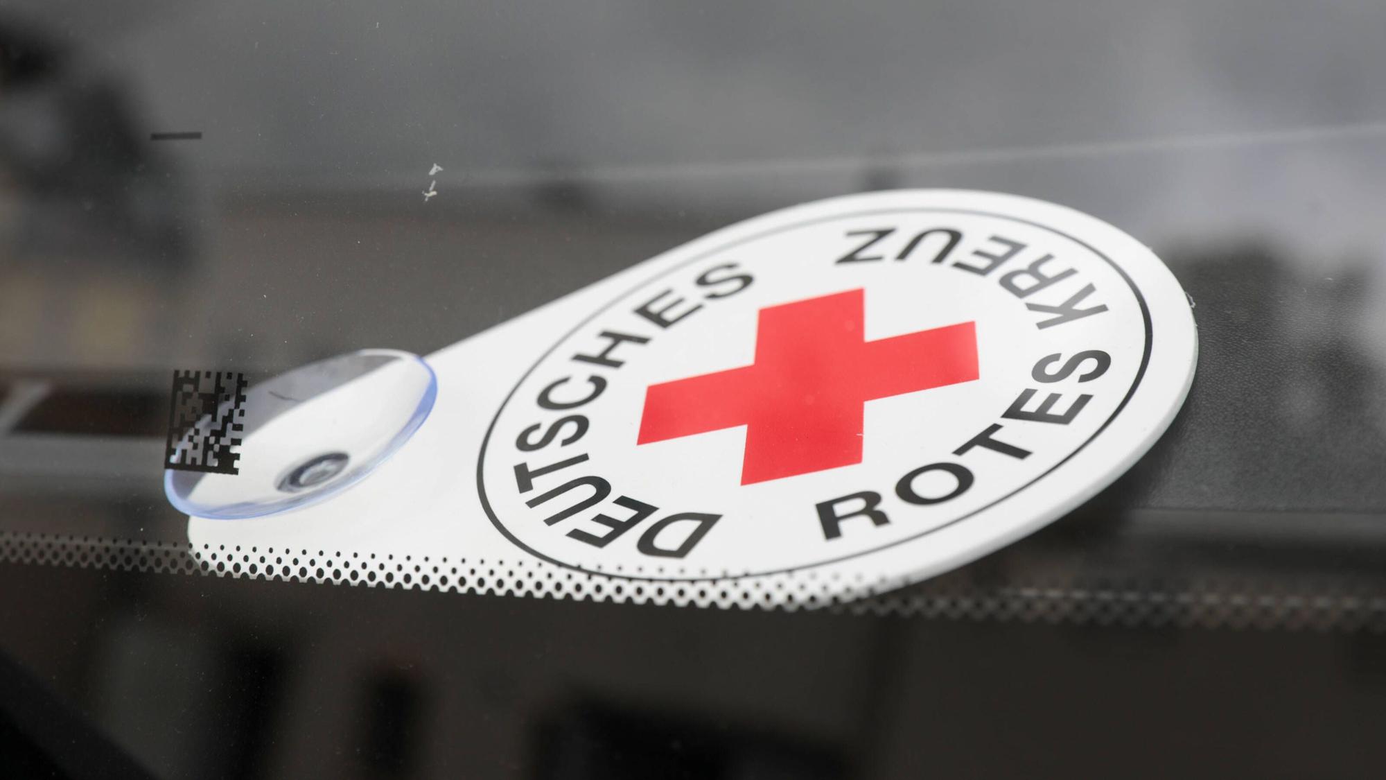 Autoschild Deutsches Rotes Kreuz liegt hinter der Frontscheibe eines Fahrzeuges des Katastrophenschutzes.