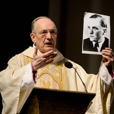 Der Geistliche Helmut Moll spricht in der Euskirchener Herz-Jesu-Kirche über  Willi Graf und hält ein Foto in der Hand, das den Widerstandskämpfer zeigt.