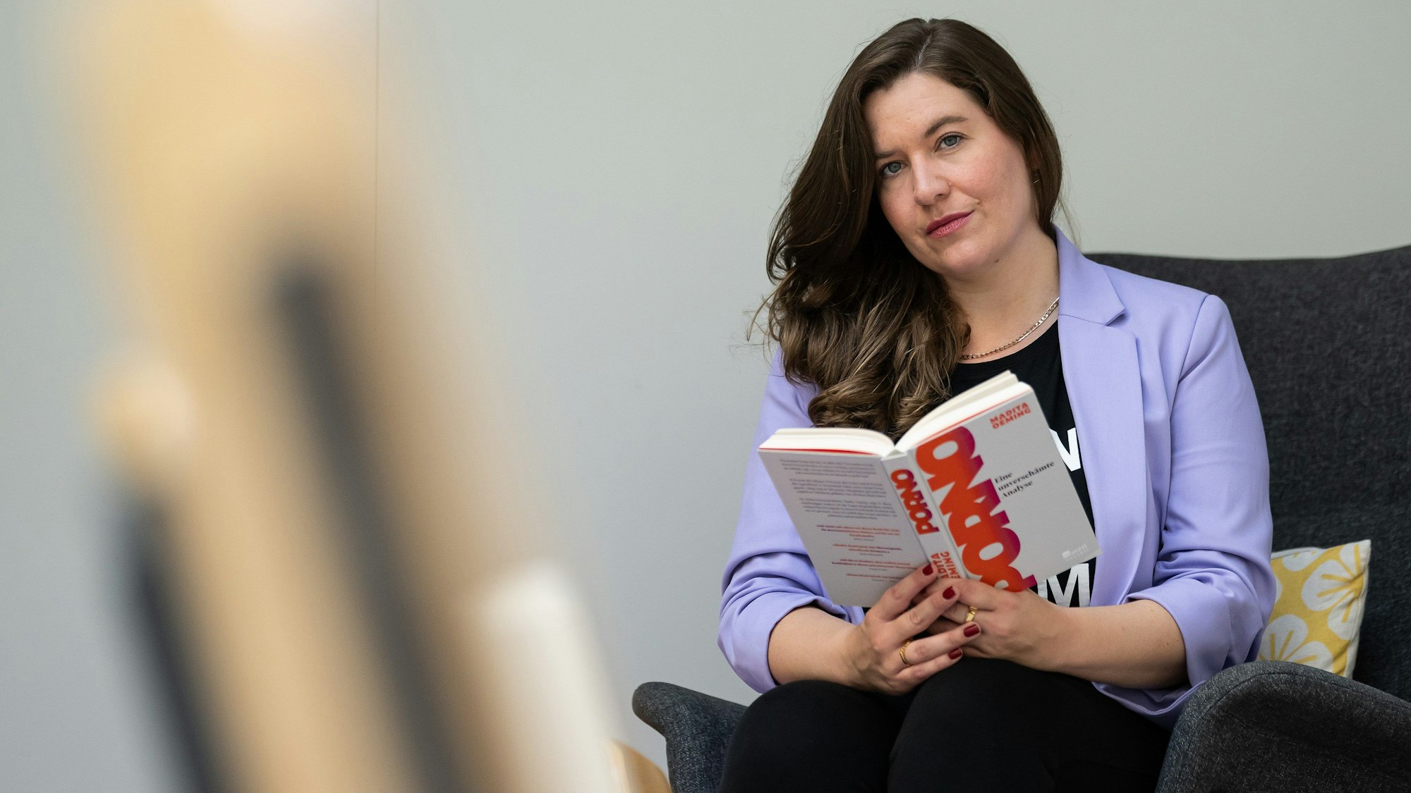 Die unabhängige Pornowissenschaftlerin Madita Oeming sitzt mit ihrem neuen Buch "Porno. Eine unverschämte Analyse" auf einem Sessel.