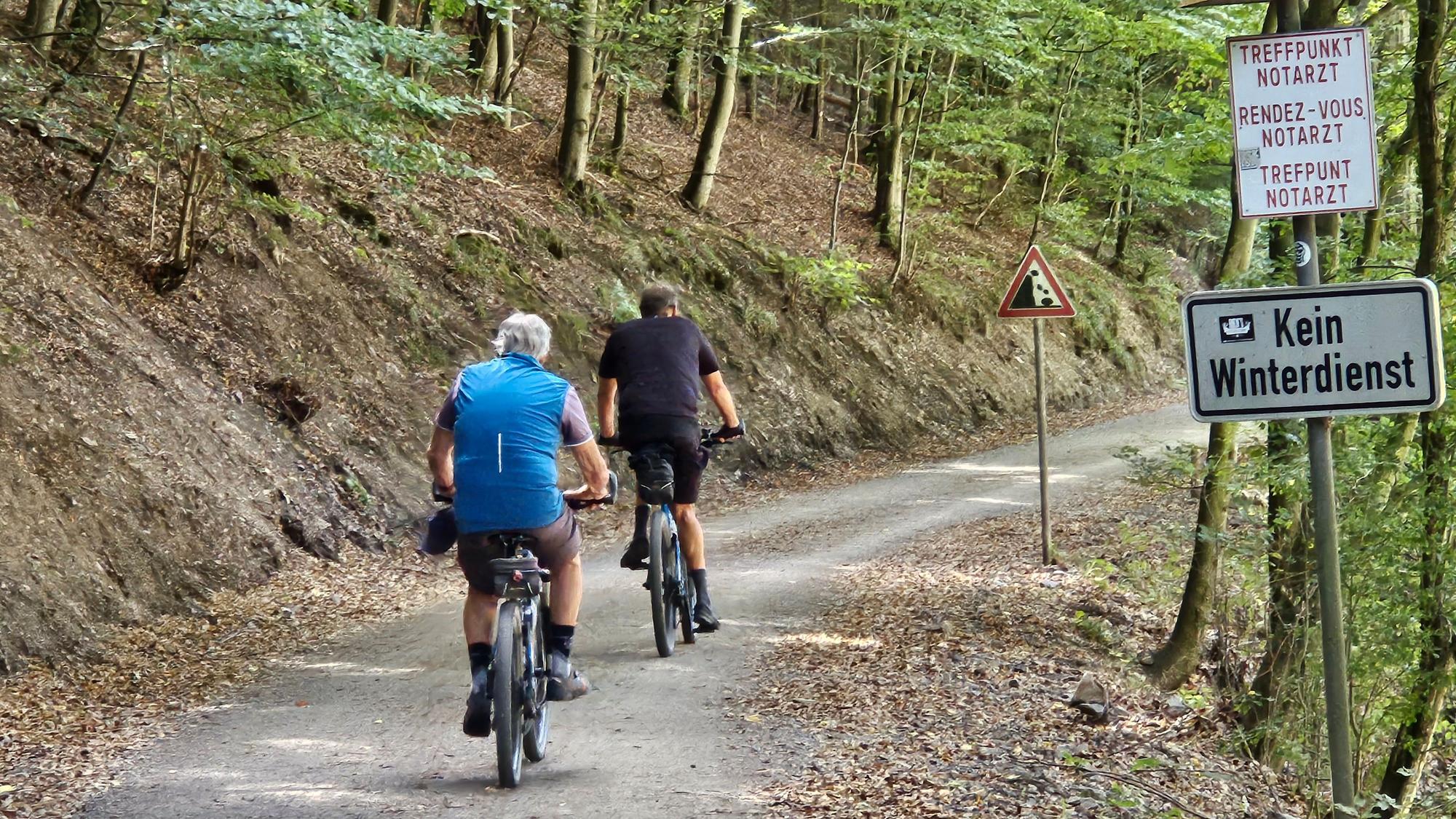 Zwei Radfahrer sind auf dem Weg unterwegs.