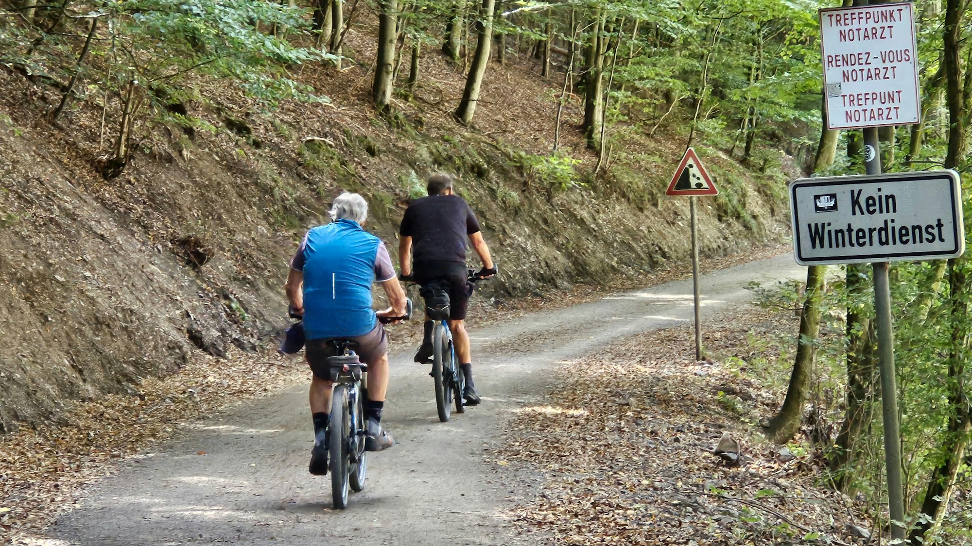 Zwei Männer fahren im Wald mit dem Fahrrad.