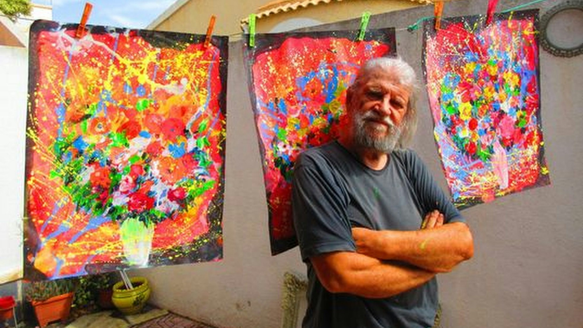 Maler Eugen Daub vor einigen seiner bunten Bilder.