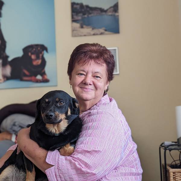 Eine Frau mit ihrem Hund in ihrem Wohnzimmer vor einem Hundefoto.