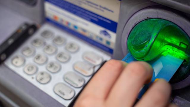 Eine Bankkundin steckt ihre Girokarte in einen Geldautomaten.