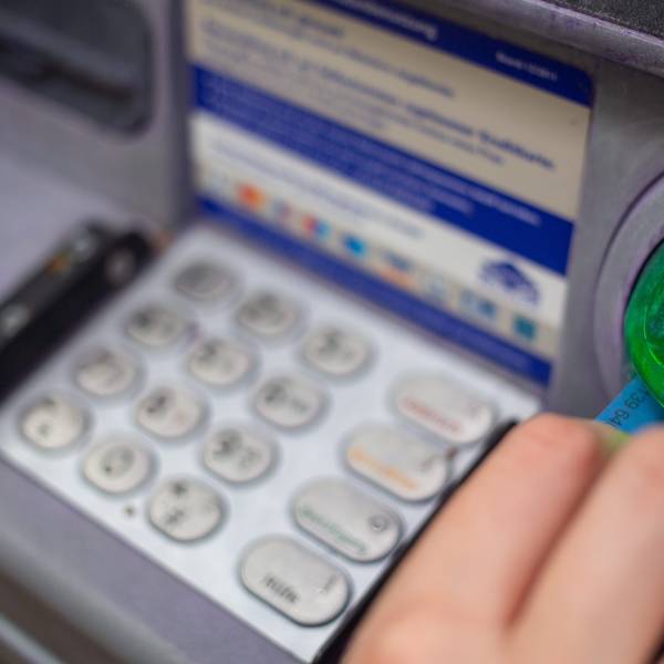 Eine Bankkundin steckt ihre Girokarte in einen Geldautomaten.
