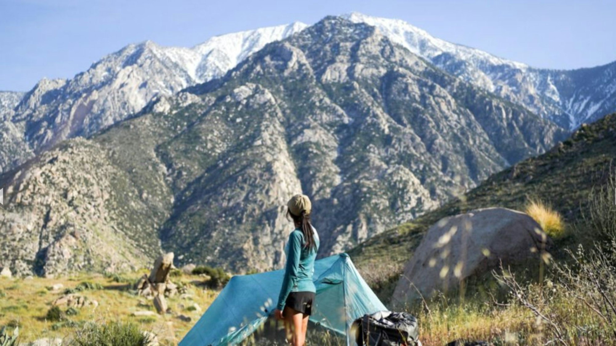 Eine Frau schaut auf schneebedeckte Gipfel einer Bergkette.