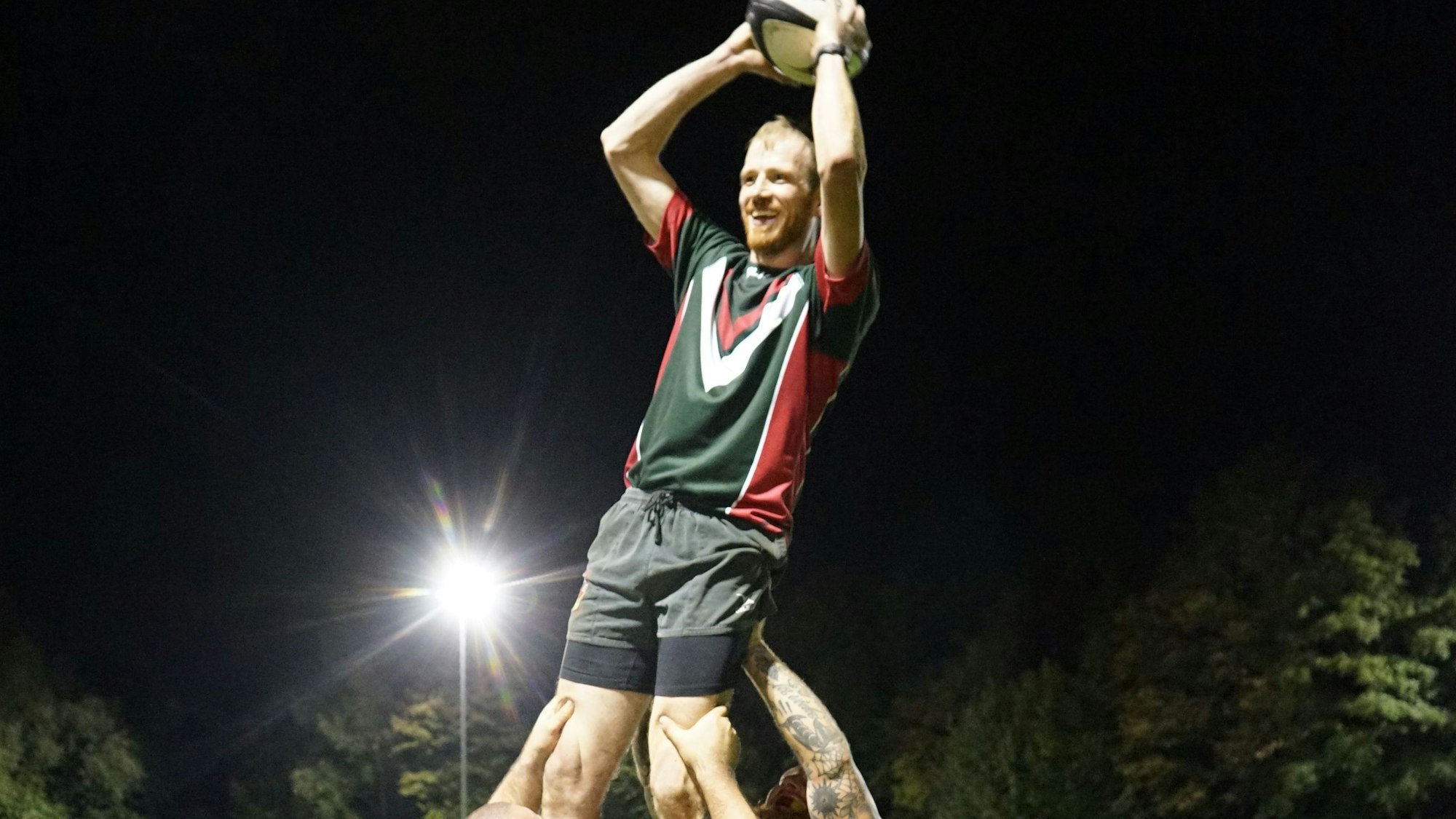 Ein Mann mit einem Ball in der Hand wird hochgehoben.