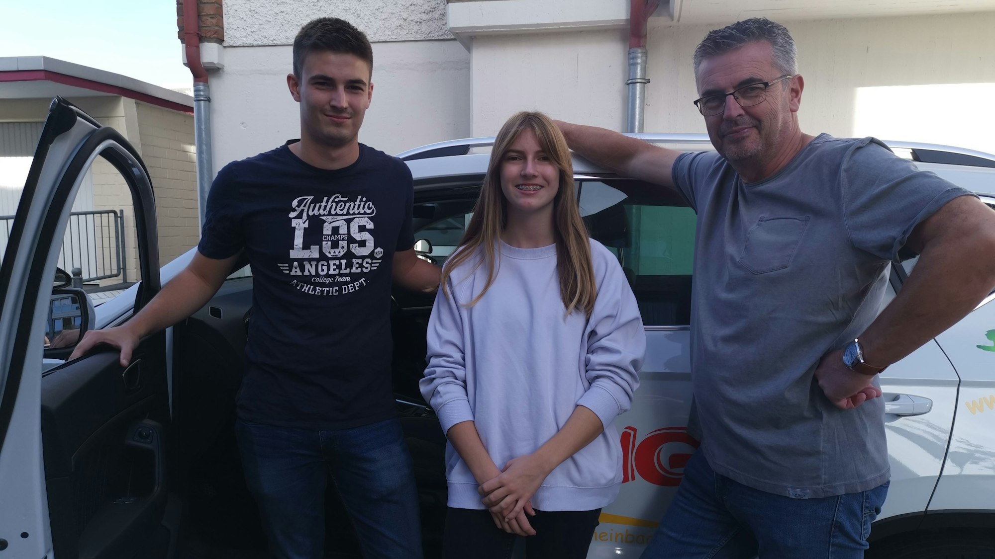 Drei Personen stehen vor einem Auto