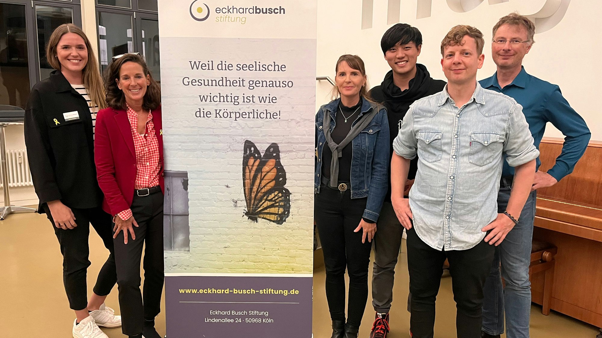 Drei Frauen und drei Männer stehen um einen Aufsteller herum, der auf die Eckhard-Busch-Stiftung hinweist