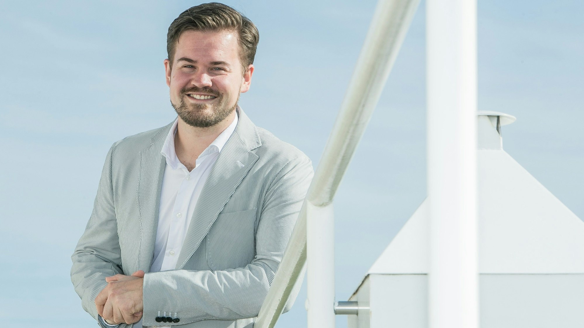 Bild eines Mannes, im Hintergrund ein großes weißes Kreuz.