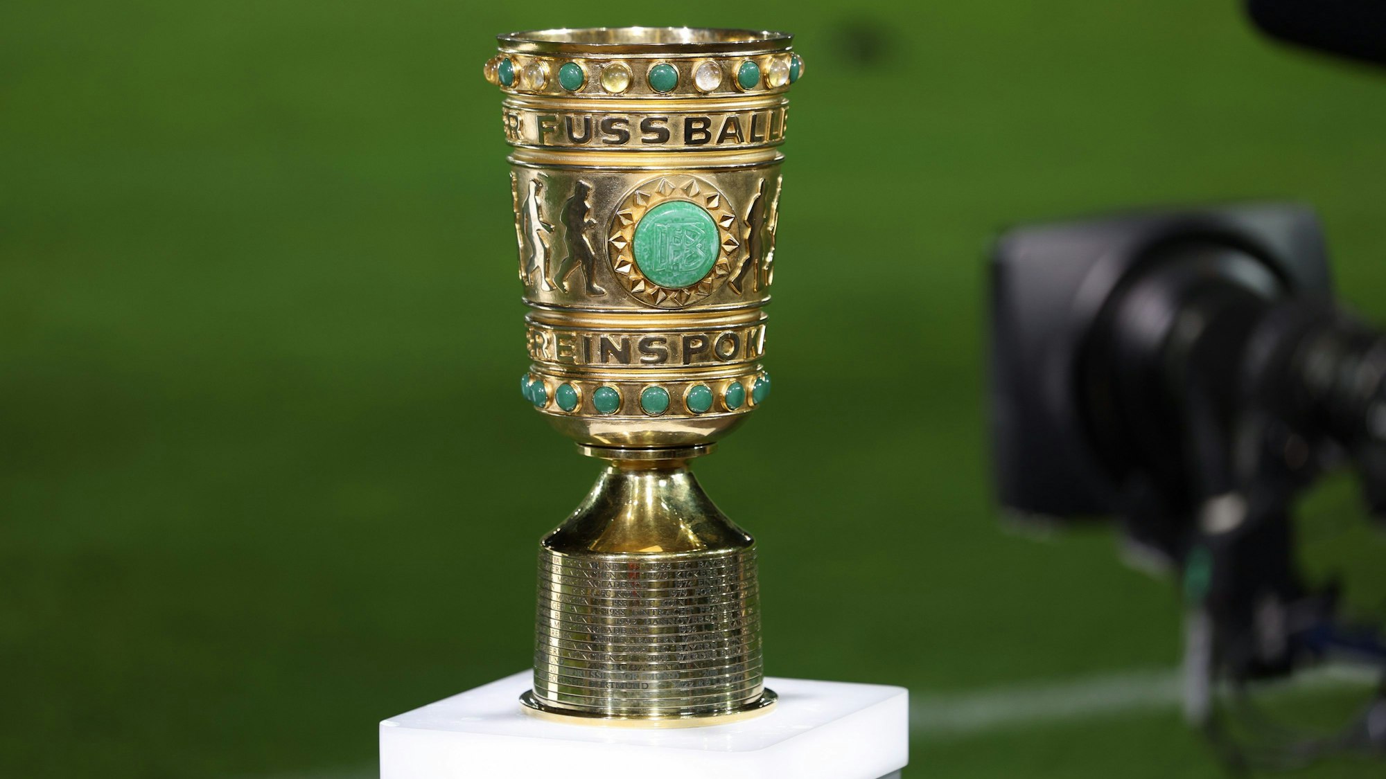 ARCHIV - 26.09.2023, Nordrhein-Westfalen, Münster: Fußball: DFB-Pokal, Preußen Münster - Bayern München, 1. Runde im Preußenstadion. Eine Abbildung des DFB-Pokals steht am Spielfeldrand mit einer TV-Kamera davor. Die ARD zeigt live das Zweitrunden-Spiel des FC Bayern in Saarbrücken, das ZDF ist beim 1. FC Kaiserslautern gegen den 1. FC Köln dabei. Und der Pay-TV-Sender Sky zeigt alle 16 Partien um den Einzug ins Achtelfinale. (zu dpa: «Pokal im Free-TV: Bayern in Saarbrücken und Lautern gegen Köln») Foto: Friso Gentsch/dpa +++ dpa-Bildfunk +++