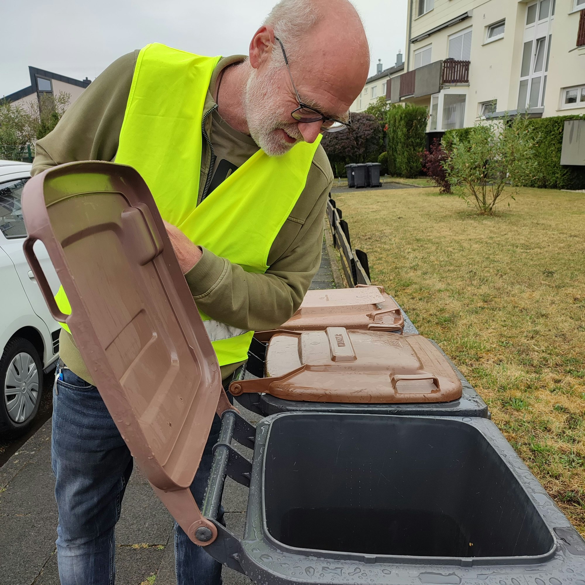 Ein Prüfer schaut in eine Biotonne..