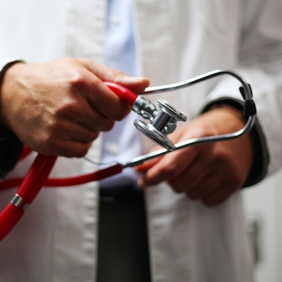 Ein Arzt in weißem Kittel hält ein Stethoskop in den Händen.