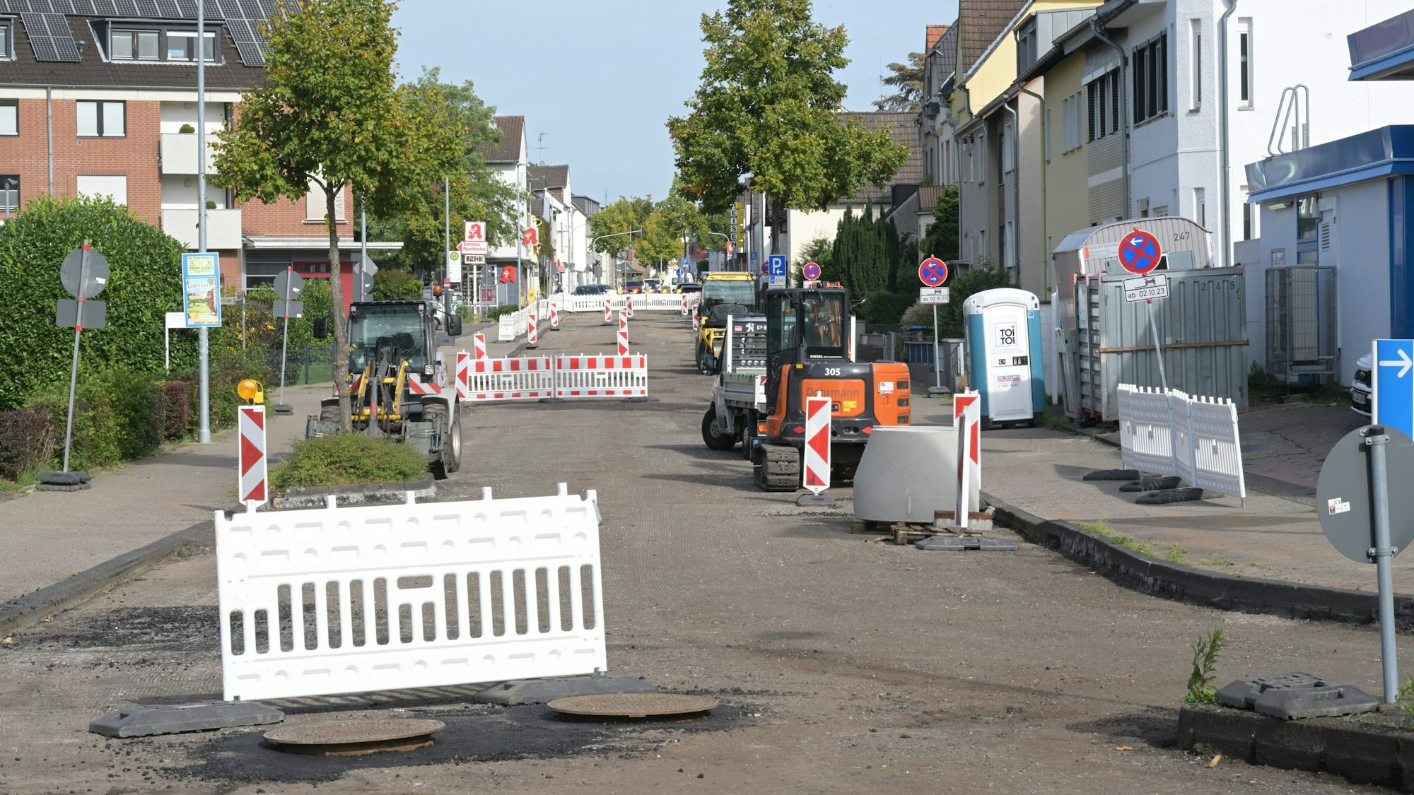 Warnbaken stehen auf einer Straße, deren Oberfläche abgefräst ist.