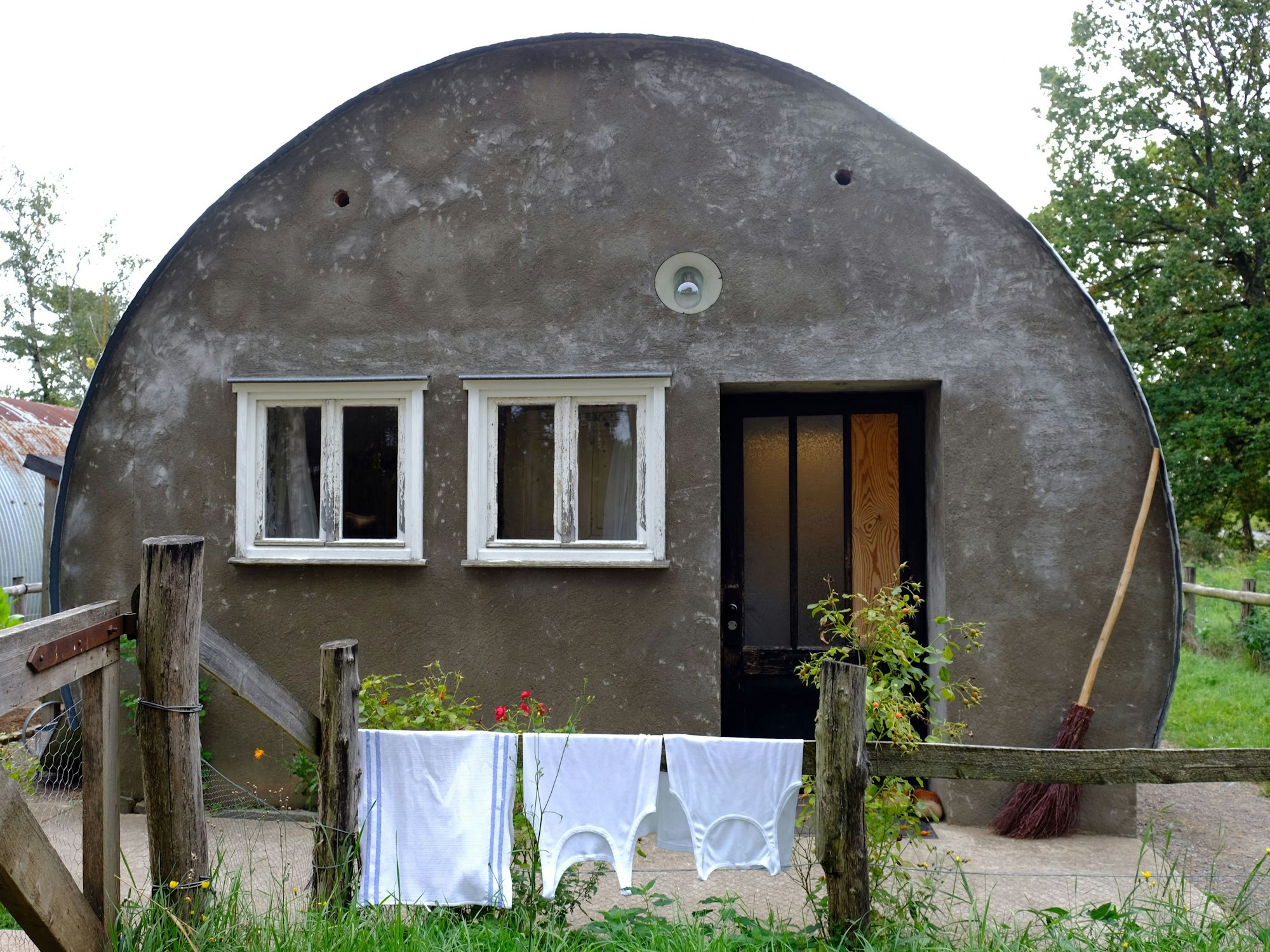 Die Frontseite einer Nissenhütte im Freilichtmuseum Kommern. Auf dem Zaun davor hängen zwei Unterhemden und ein Küchentuch zum Trocknen.