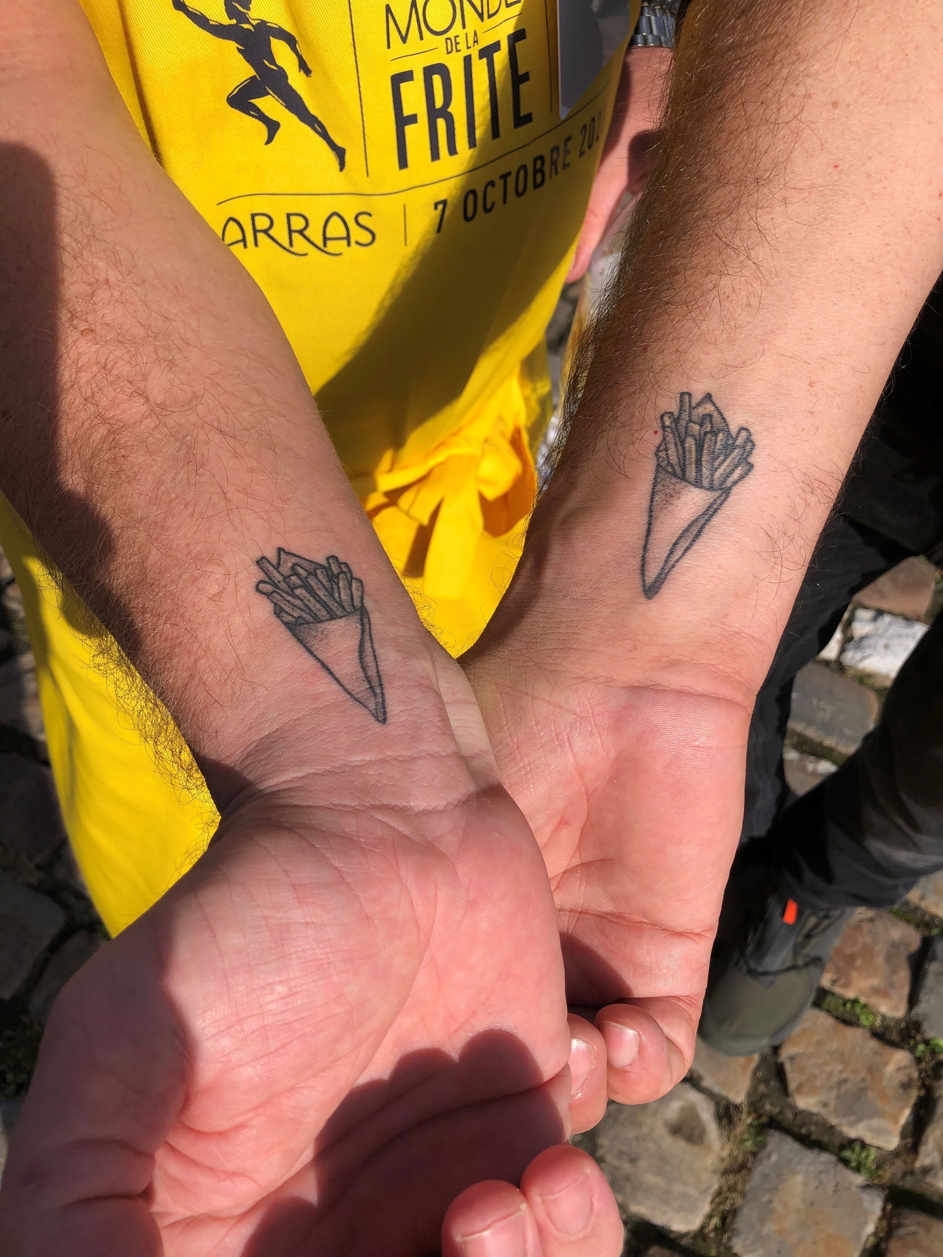 Die beiden belgischen Gastronomen Fabian Frances (l) und Sébastian Viloria (r) haben sich eine Pommes-frites-Tüte auf das Handgelenk tätowieren lassen.