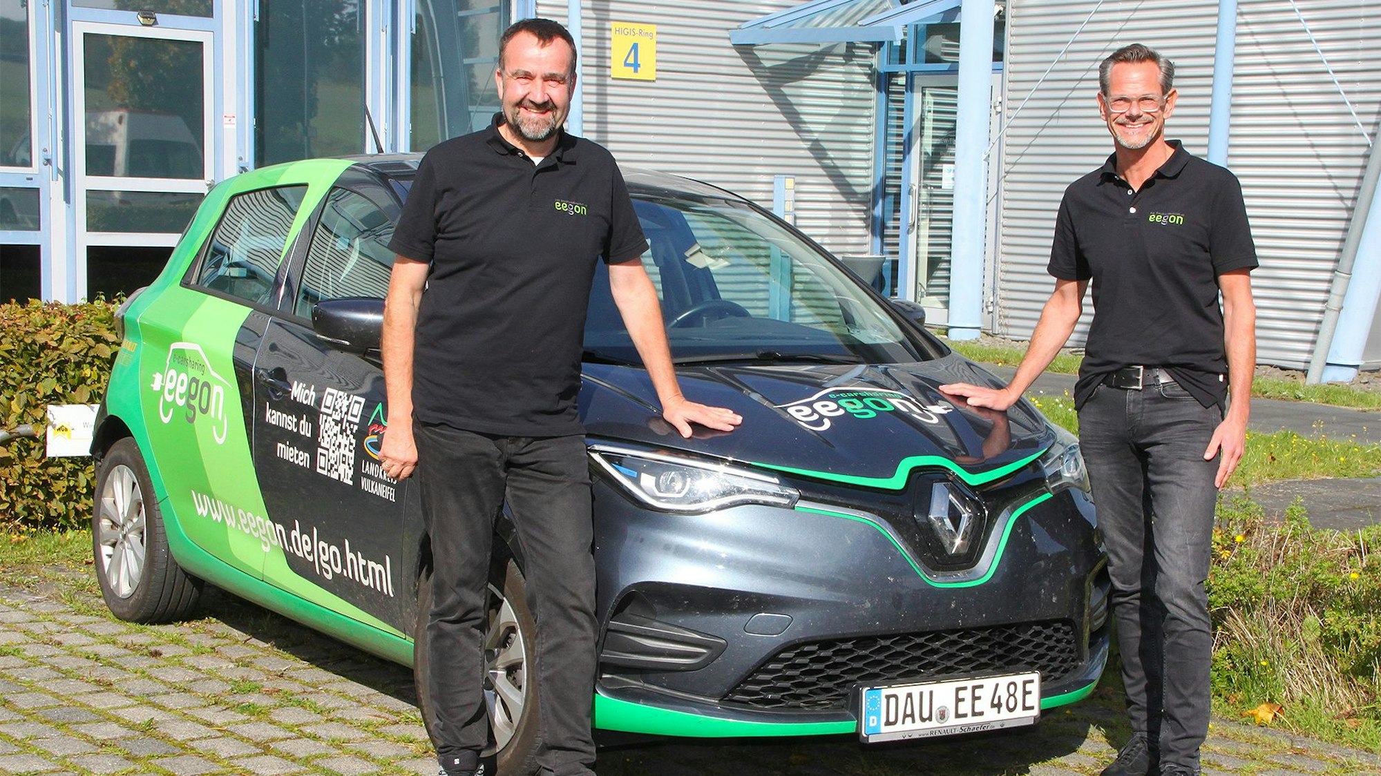 Die beiden Geschäftsführer vor ihrem mit den Firmen-Logos gekennzeichneten E-Dienstwagen.