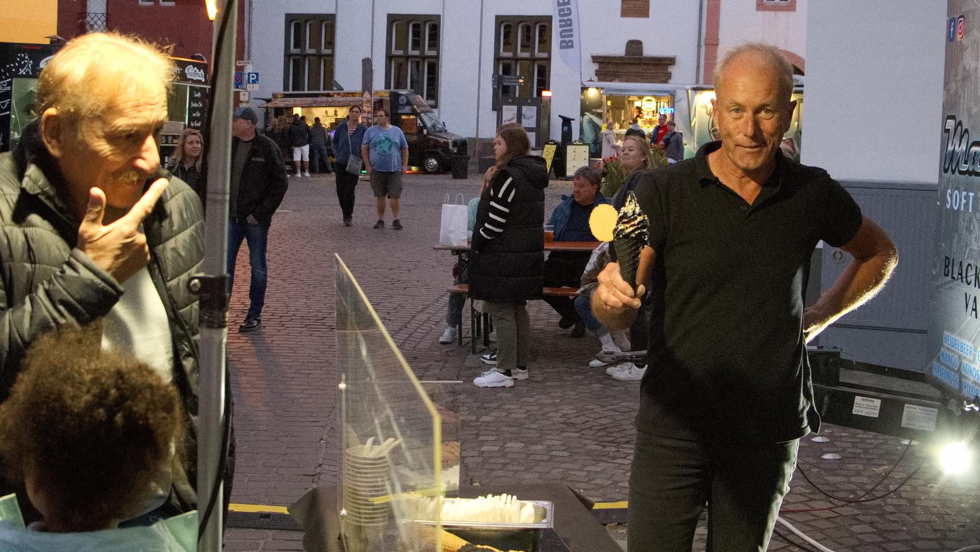 Rainer Ober hält ein schwarzes Softeis in die Kamera.