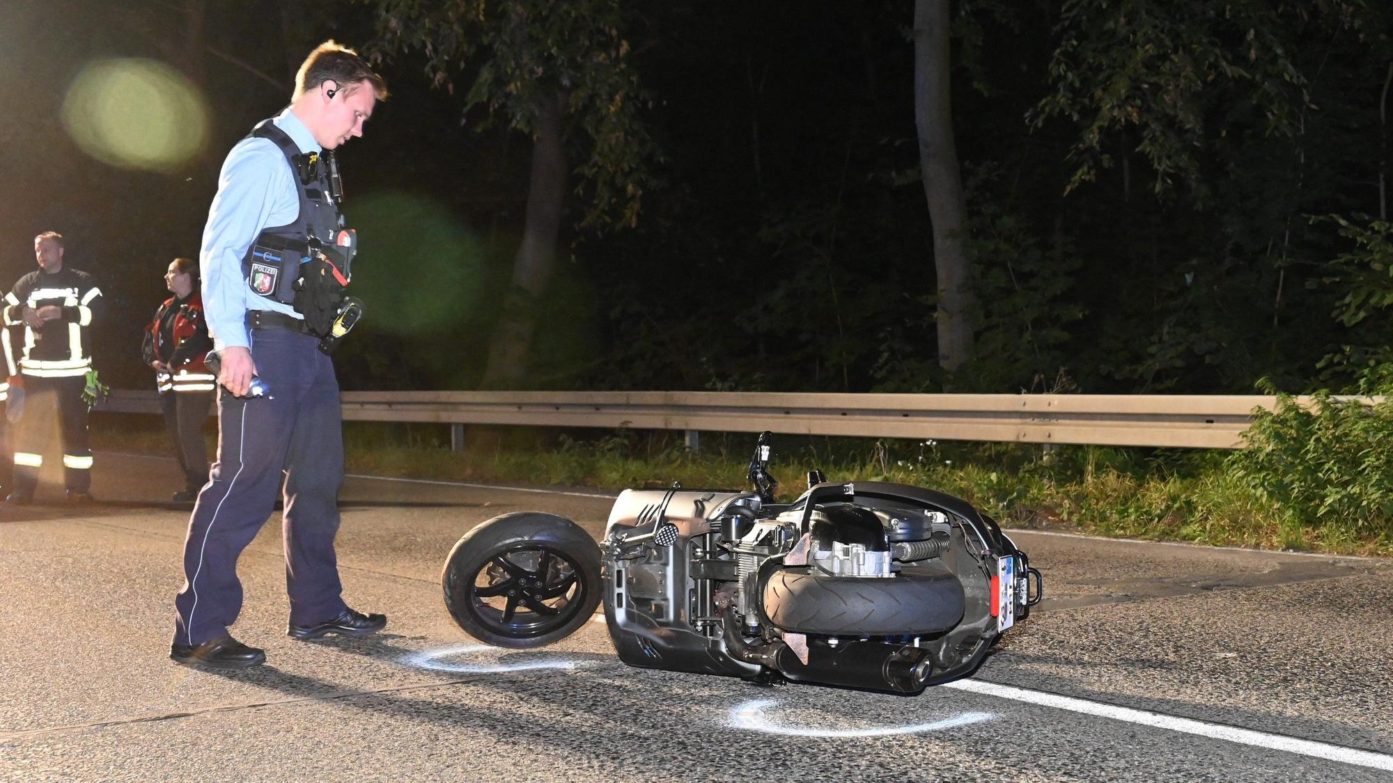 Ein Polizist steht neben einem Motorroller.