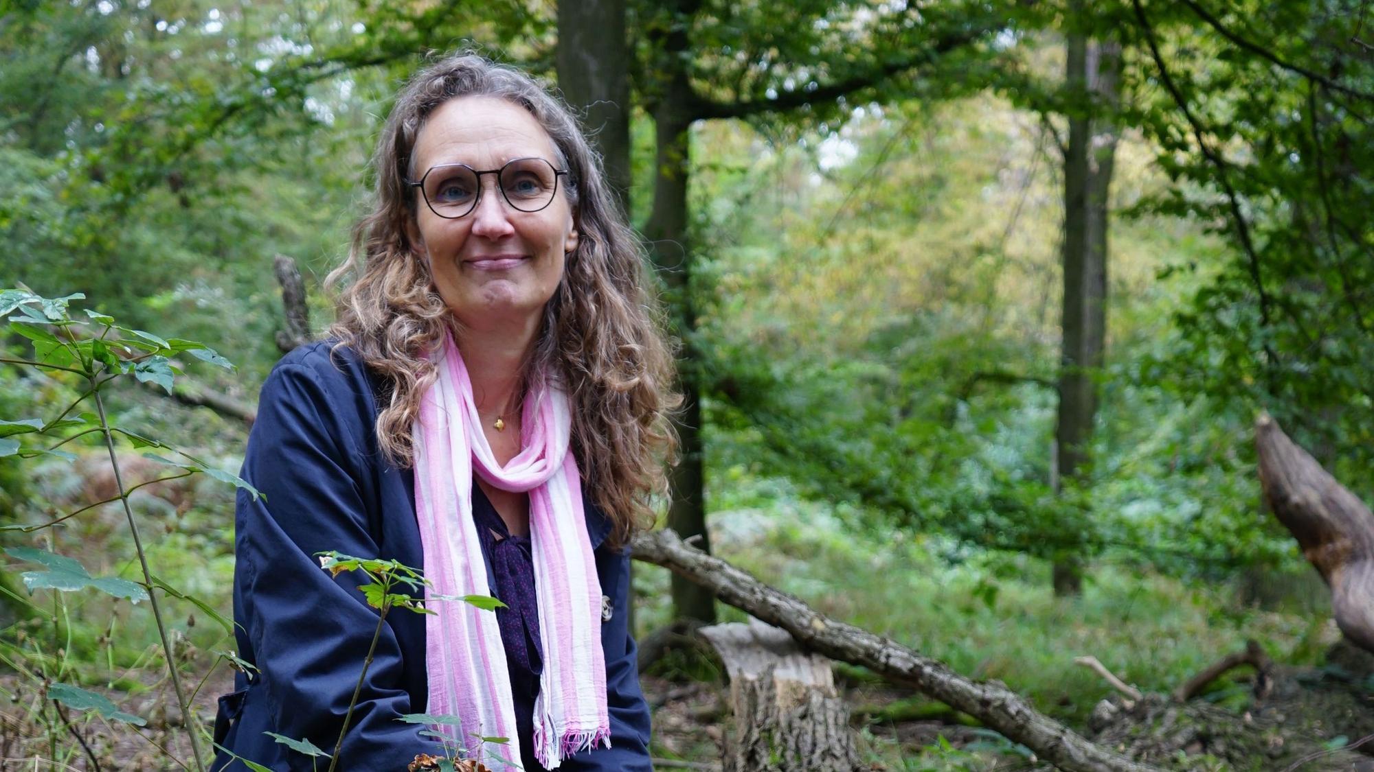 Eine Frau sitzt in einem Wald.