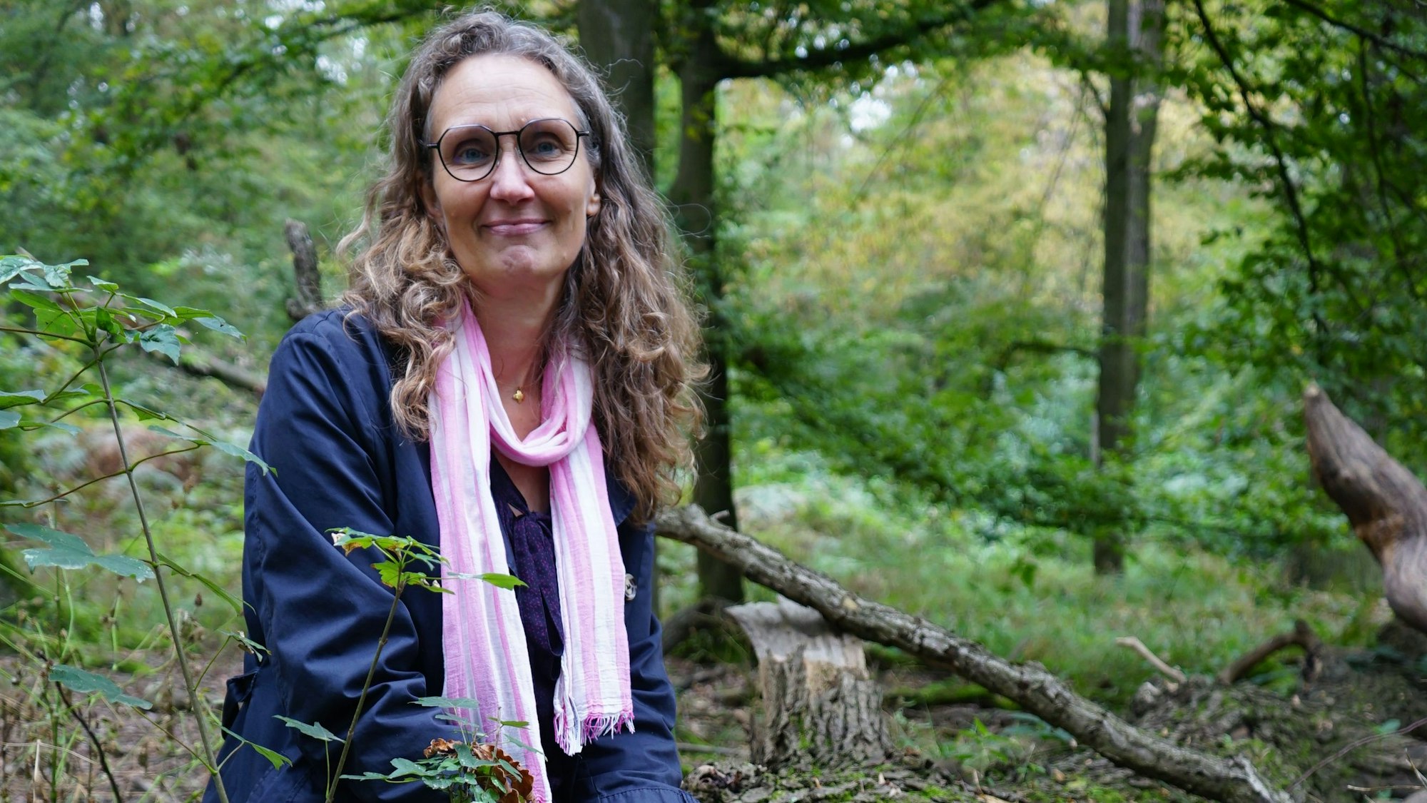 Auf dem Foto ist eine Frau zu sehen, sie befindet sich in einem Wald.