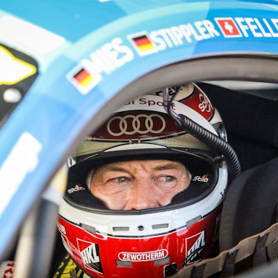 Rennfahrer Frank Stippler sitzt, mit geöffnetem Visier, in seinem Rennwagen.