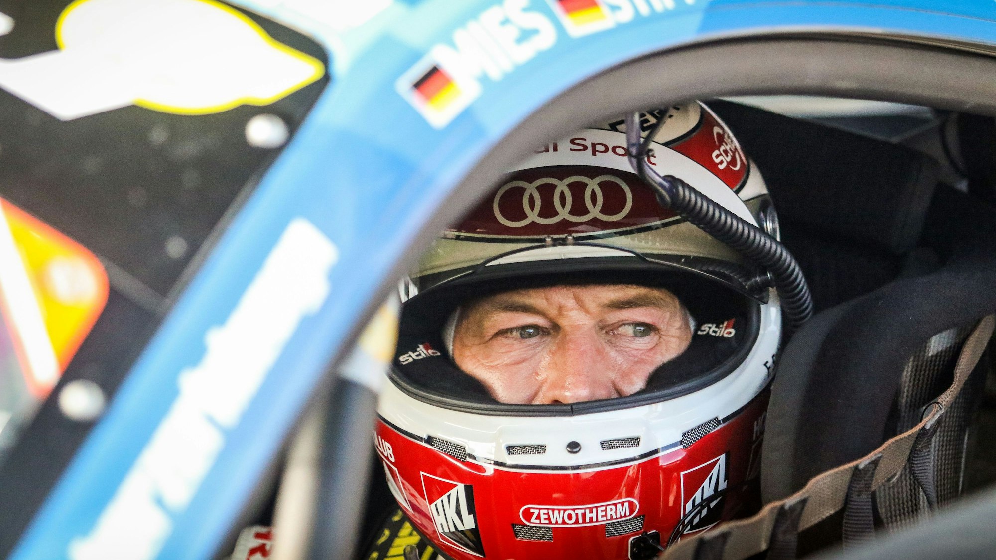 Frank Stippler sitzt in seinem Rennauto und trägt einen Helm. Er blickt aus dem geöffneten Seitenfenster.