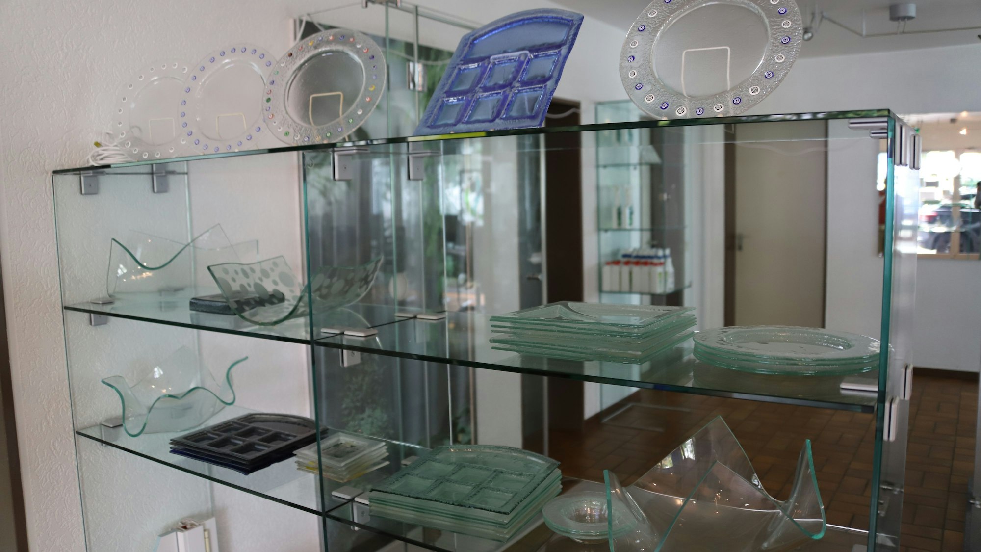 Karl-Heinz Decker (83) übergibt seinen Betrieb für Glasarbeiten an seinen Enkel Max (19). Der Betrieb macht auch Geschirr aus Glas, die hier in einer Vitrine im Firmeneingang gezeigt werden.