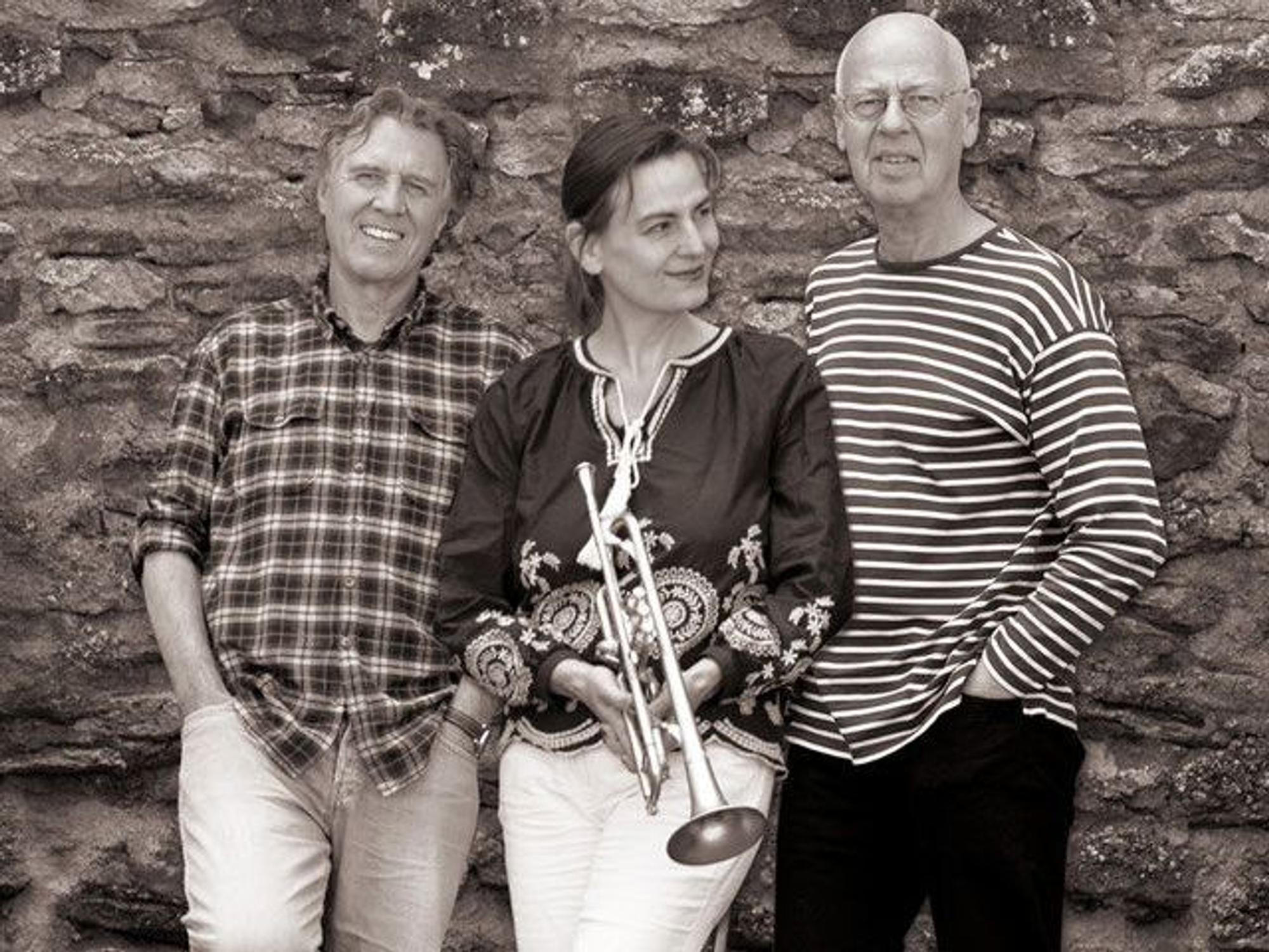 Der Schriftsteller Norbert Scheuer (l.), die Trompeterin Susanne Riemer und der Bassist Wilhelm Geschwind stehen vor einer Mauer.
