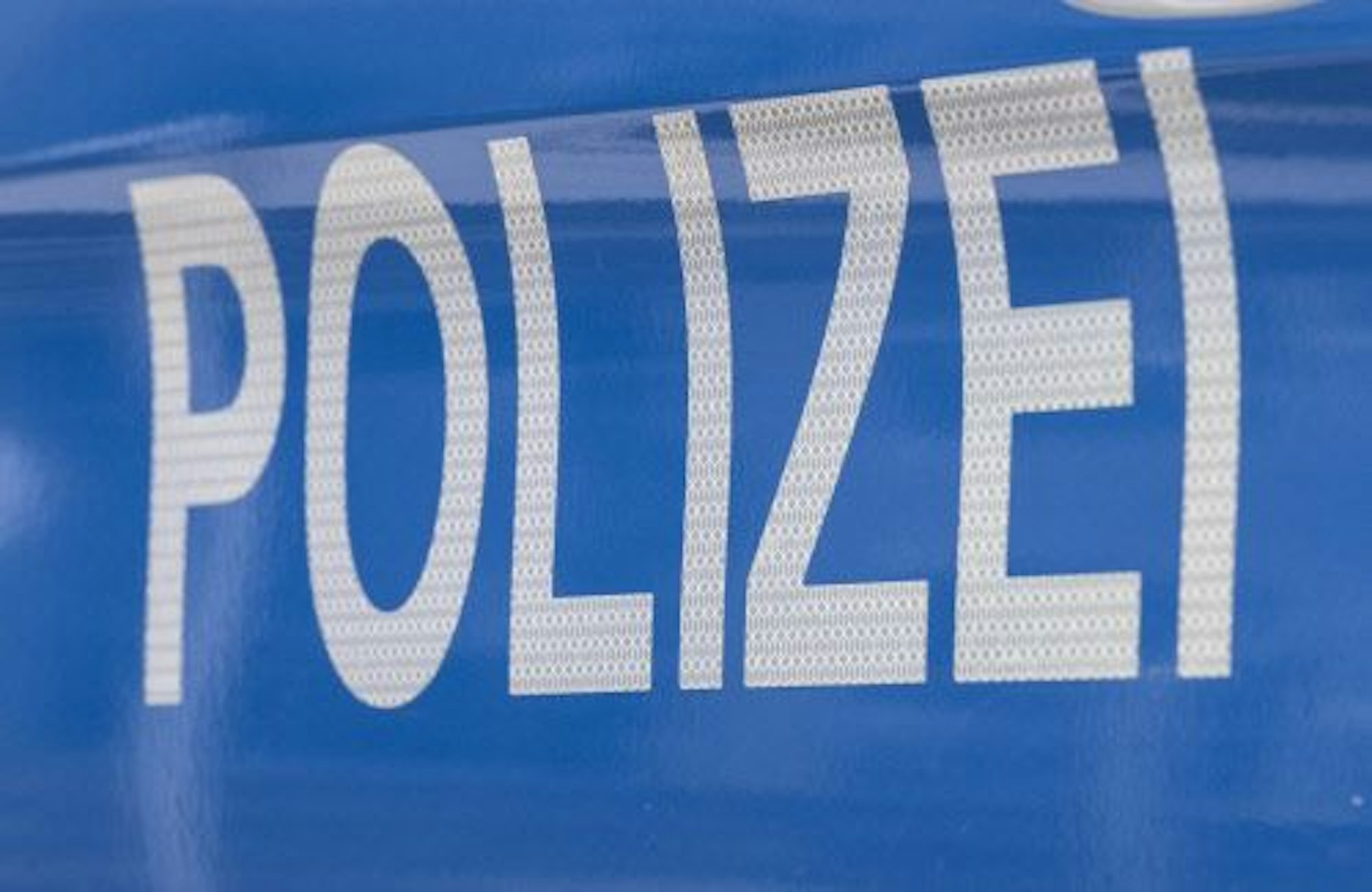 Der Schriftzug ·Polizei· ist auf einem Streifenwagen zu lesen.