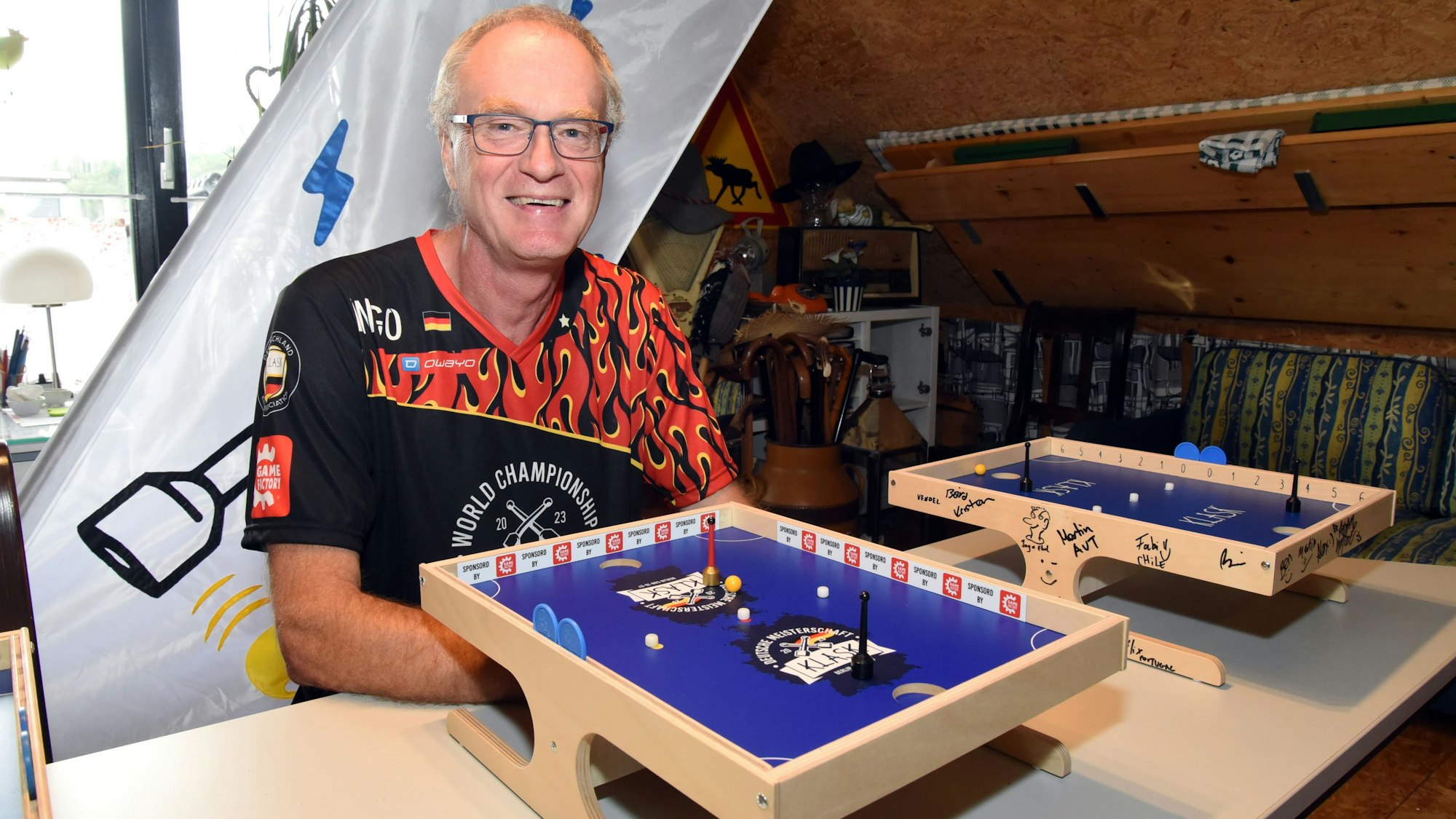 Ein Mann sitzt vor einem Klask-Spielbrett.