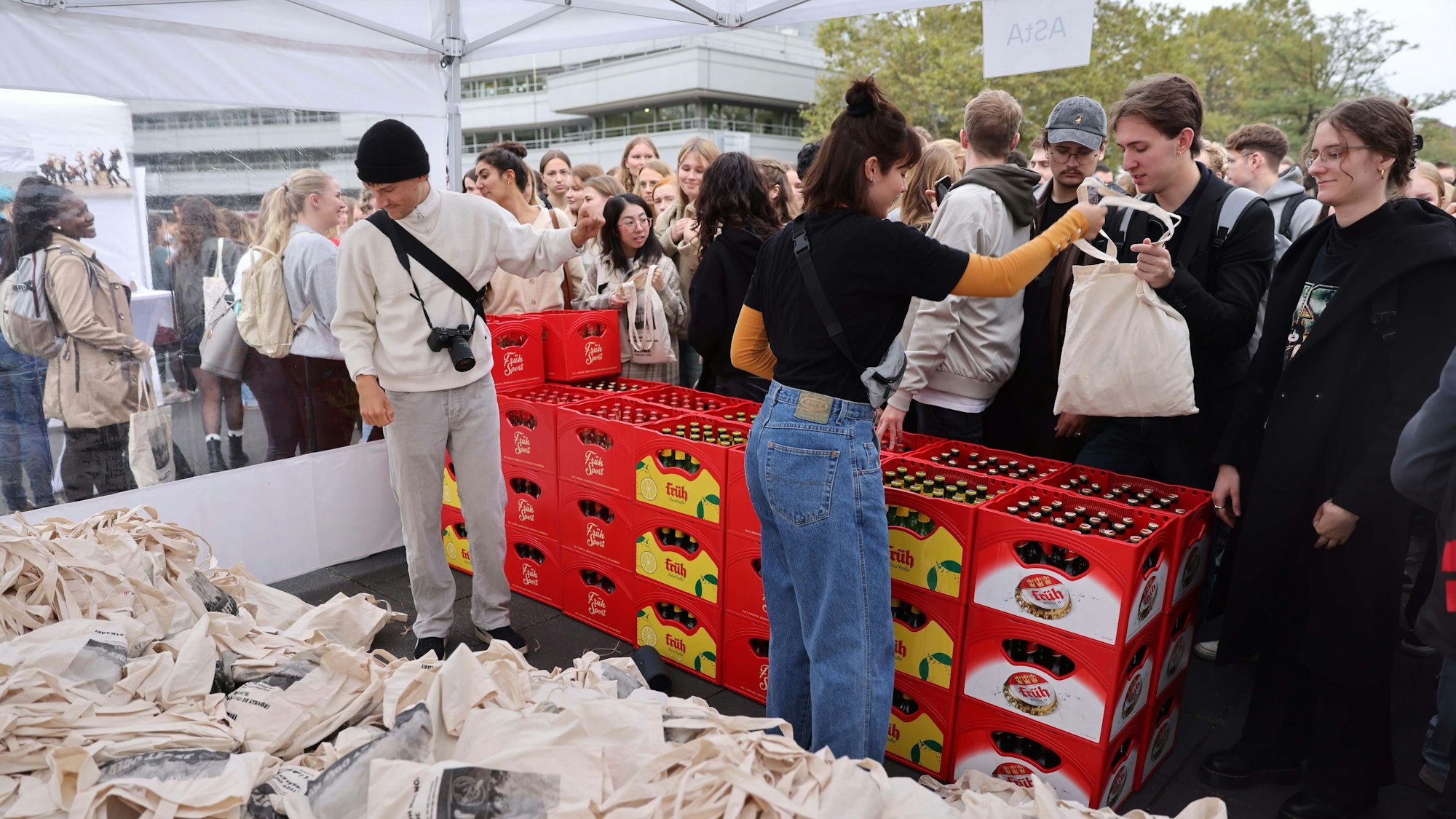 Zwei Leute geben Jutebeutel an Studierende aus.