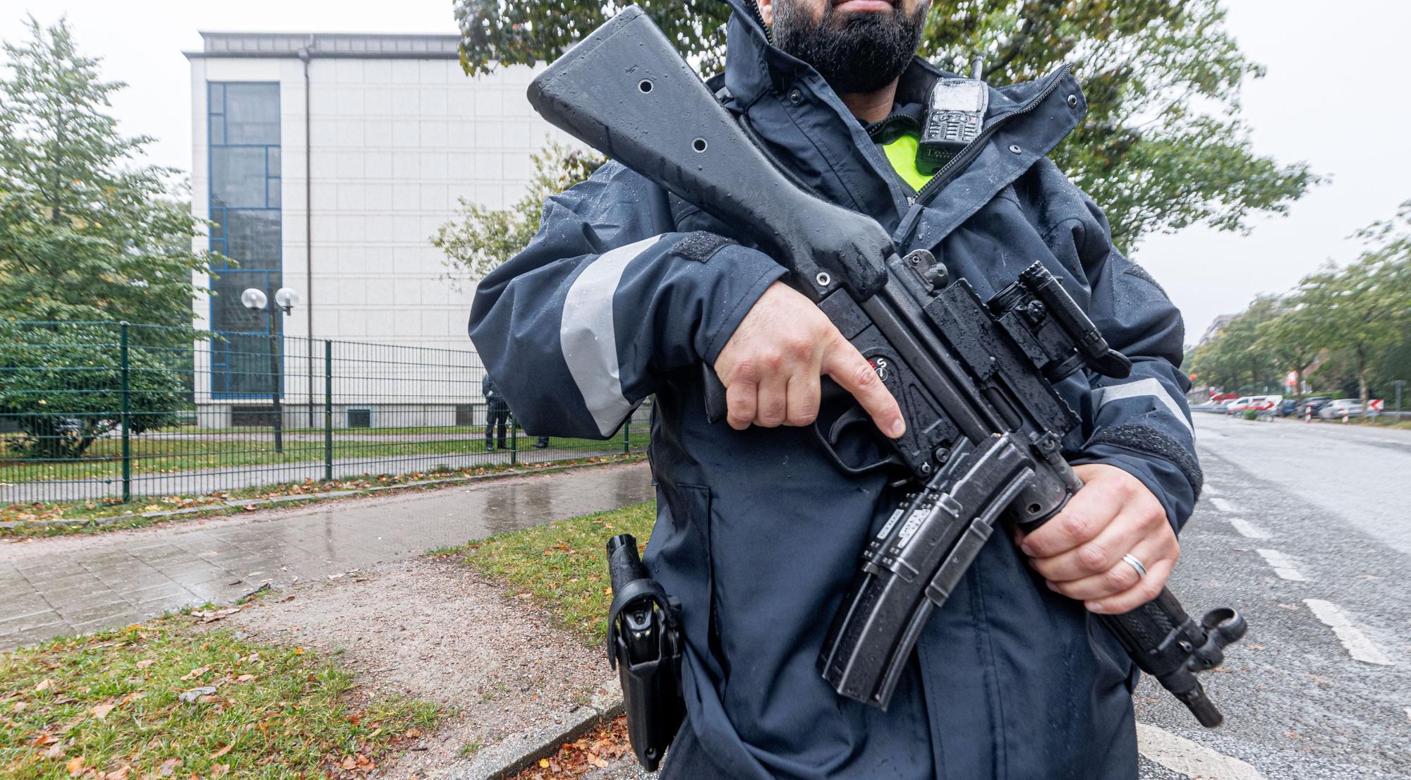 09.10.2023, Hamburg: Ein Polizist mit Maschinenpistole bewacht mit anderen nach dem Angriff der Hamas auf Israel die jüdische Synagoge in Hamburg.
