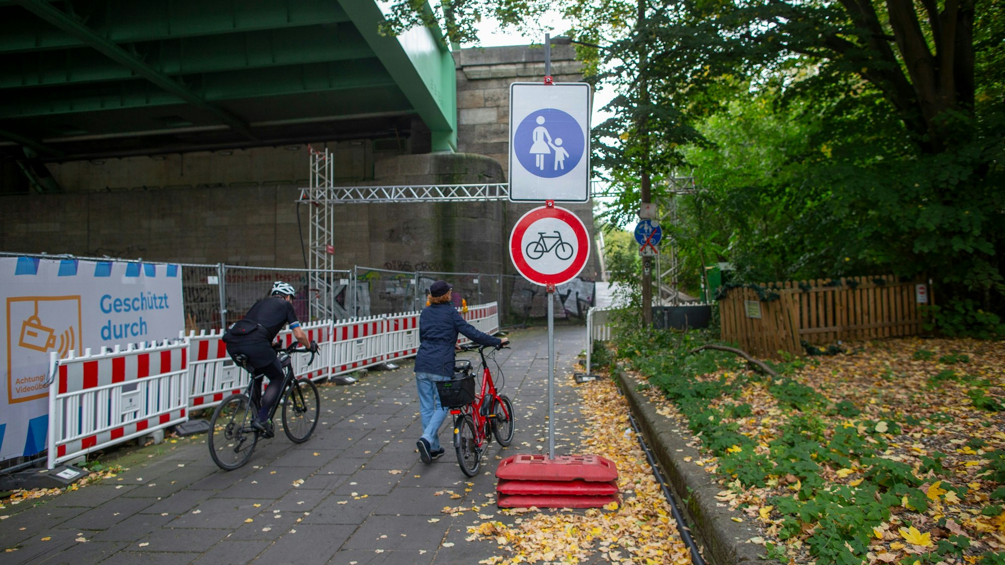 Die Verbotsschilder für Fahrradfahrende an der Rodenkirchener Brücke stehen noch. Dies sorgt für Verwirrung – auf dem Bild sieht man zwei Radfahrende nebeneinander, der eine fährt, der andere schiebt sein Rad.