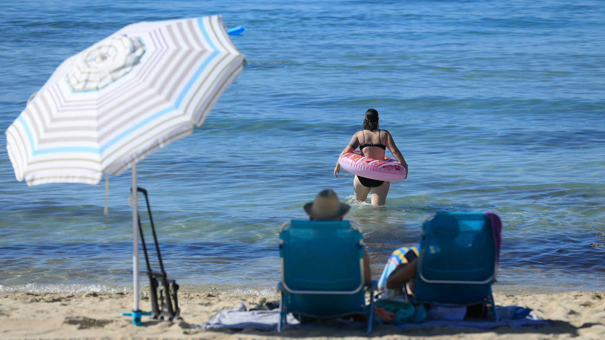 Eine Frau schwimmt mit einem Schwimmreifen im Meer am Strand von Arenal auf Mallorca am ersten Oktoberwochenende mit Temperaturen von 30 Grad.