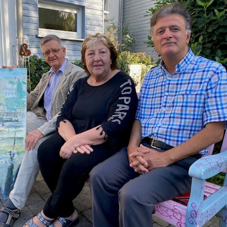 Zu sehen sind die drei Mitglieder des Arbeitskreises Palästina Brühl-Battir sowie ein Gemälde, das den Ort im Westjordanland zeigt.