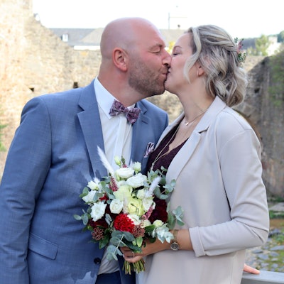 Das frisch verheiratete Ehepaar steht auf einer Brücke in Bad Münstereifel und küsst sich.