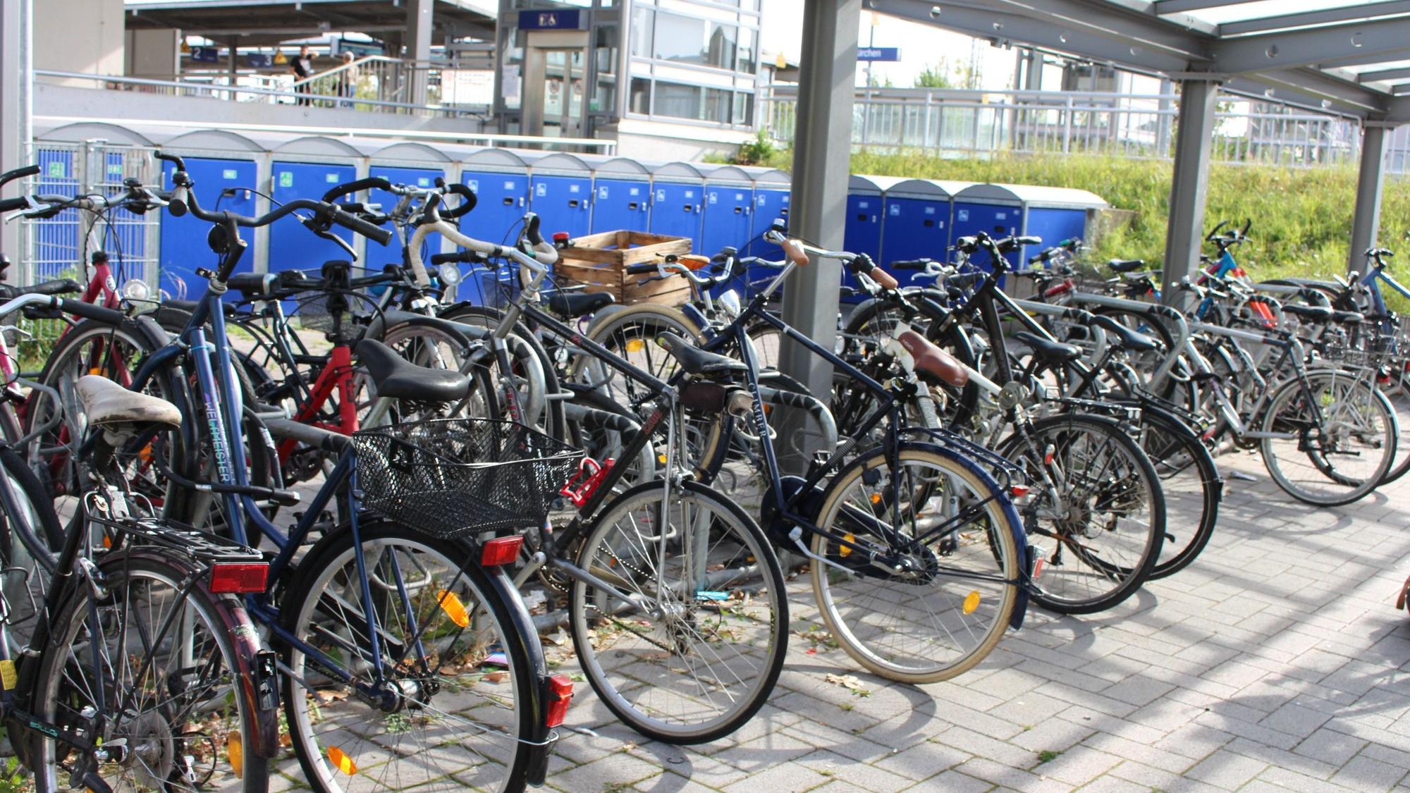 Sehr viele Fahrräder stehen in der Fahrradstation am Bahnhof, dahinter sind Boxen für Räder zu sehen.