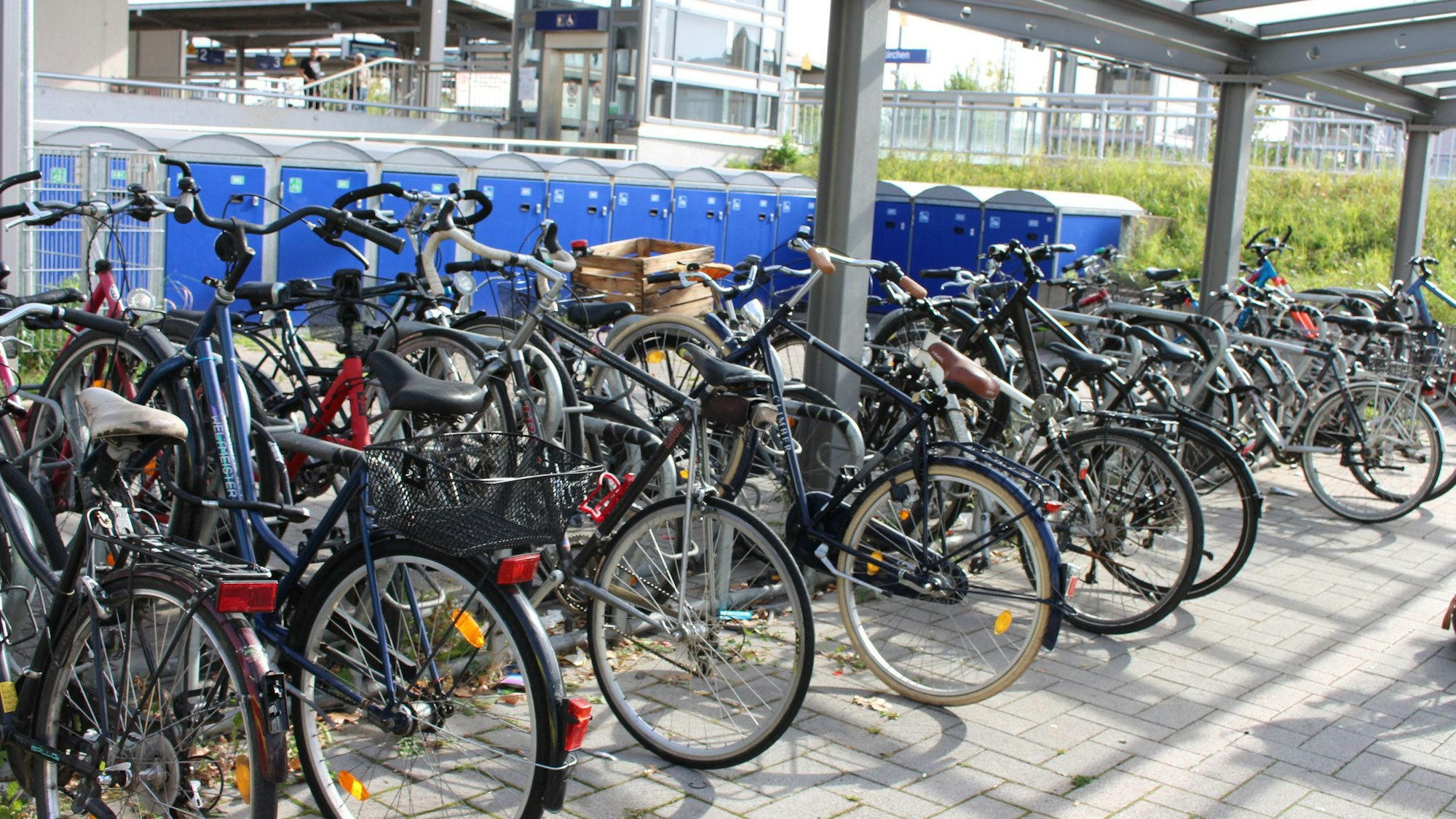 Sehr viele Fahrräder stehen in der Fahrradstation am Bahnhof, dahinter sind Boxen für Räder zu sehen.