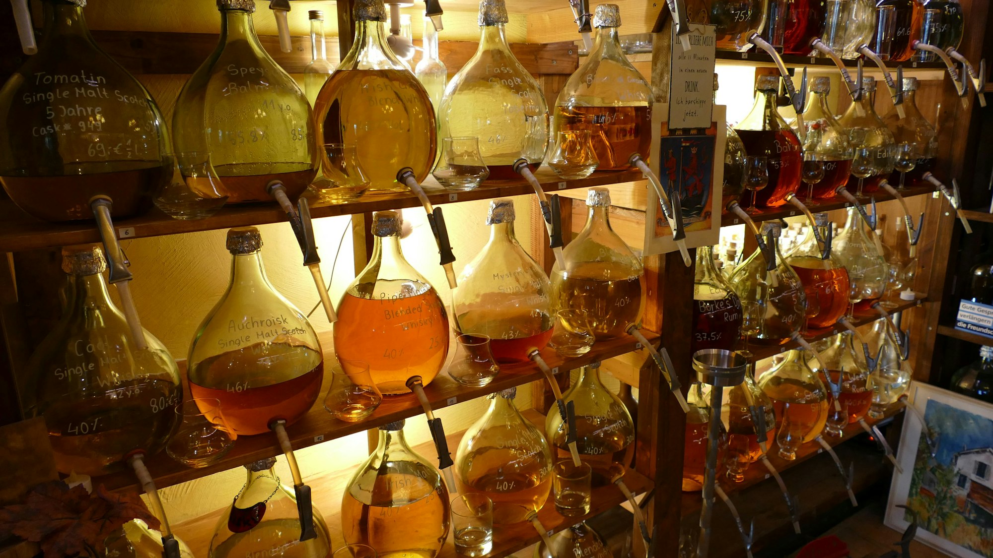 Gefäße mit bunten Flüssigkeiten darin stehen in einem Regal.