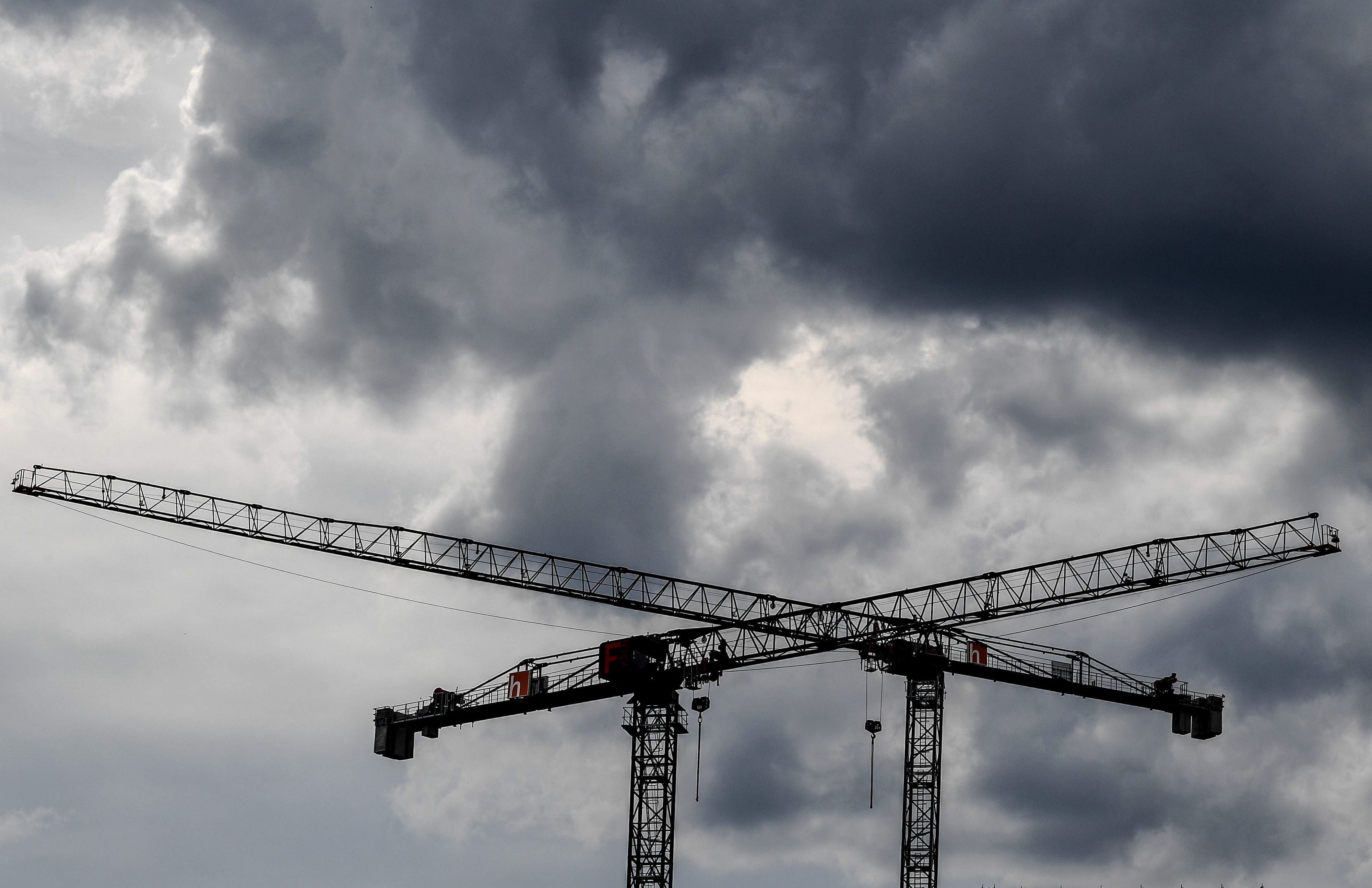 Baukräne sind vor dunklen Wolken zu sehen. (Symbolbild)