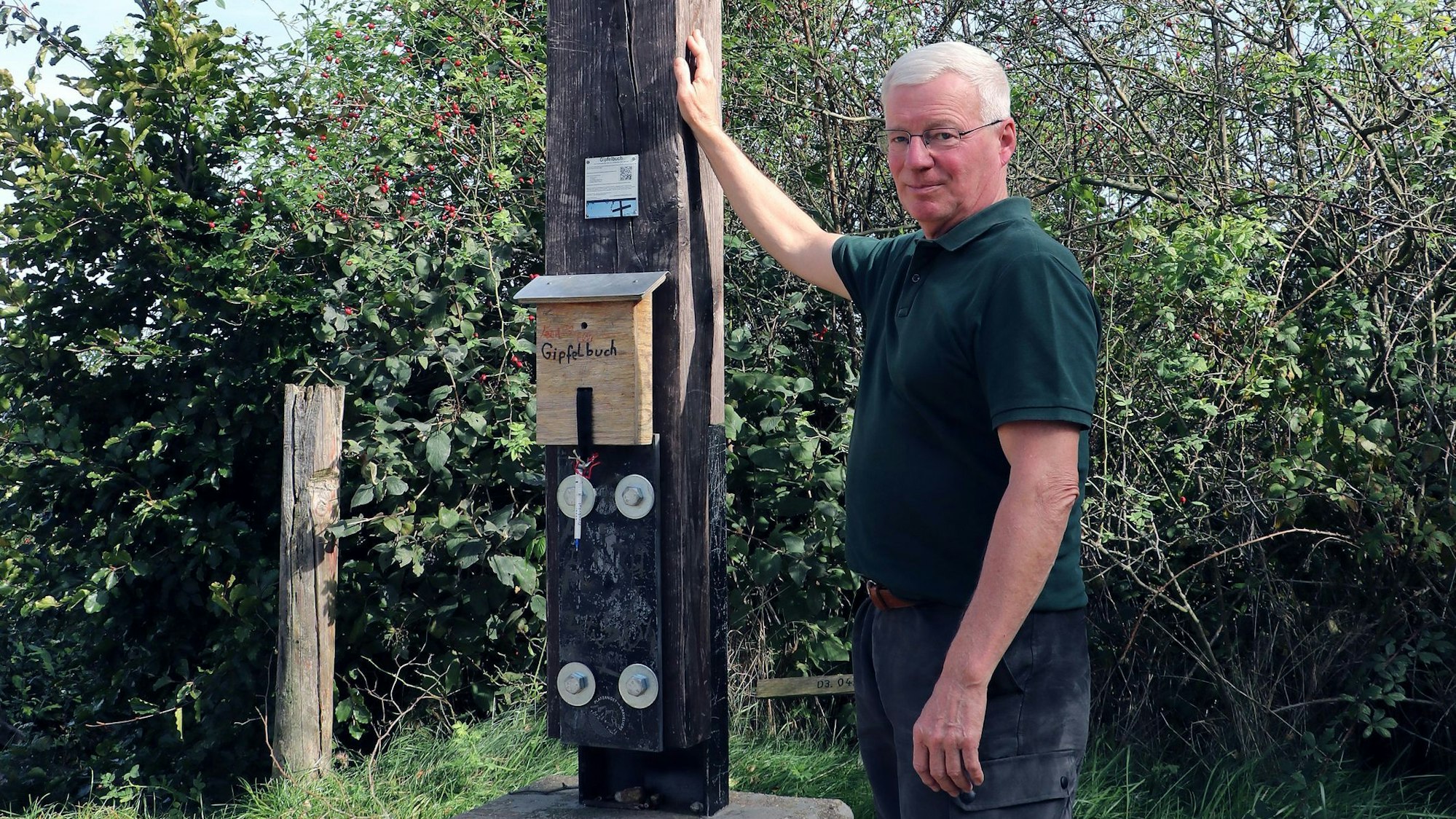 Das Bild zeigt Revierförster Theo Peters am Gipfelkreuz auf der Glessener Höhe.