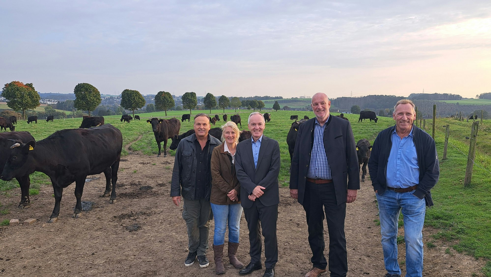 Das Foto zeigt fünf Vertreter der Kooperationspartner auf einer Weide mit Kühen.