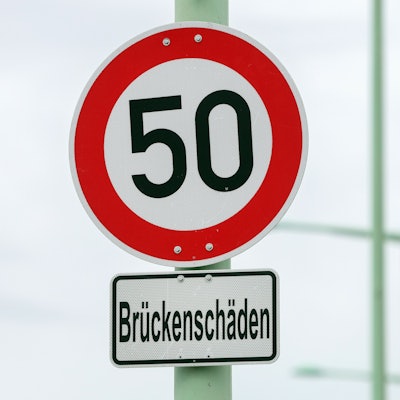 Auf einem Schild stehen 50 als zulässige Höchstgeschwindigkeit, darunter ein Hinweis auf Brückenschäden.