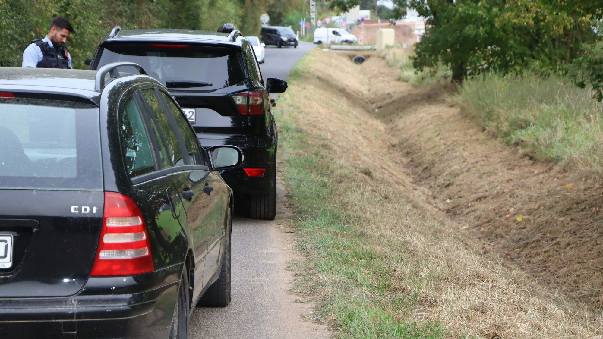 Ein Polizist hat Autos auf einem Feldweg angehalten.