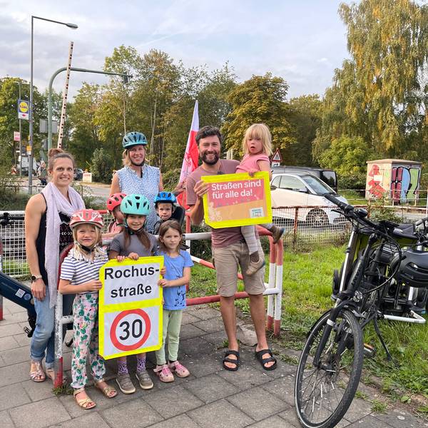Eltern stehen vor einem Bahnübergang.