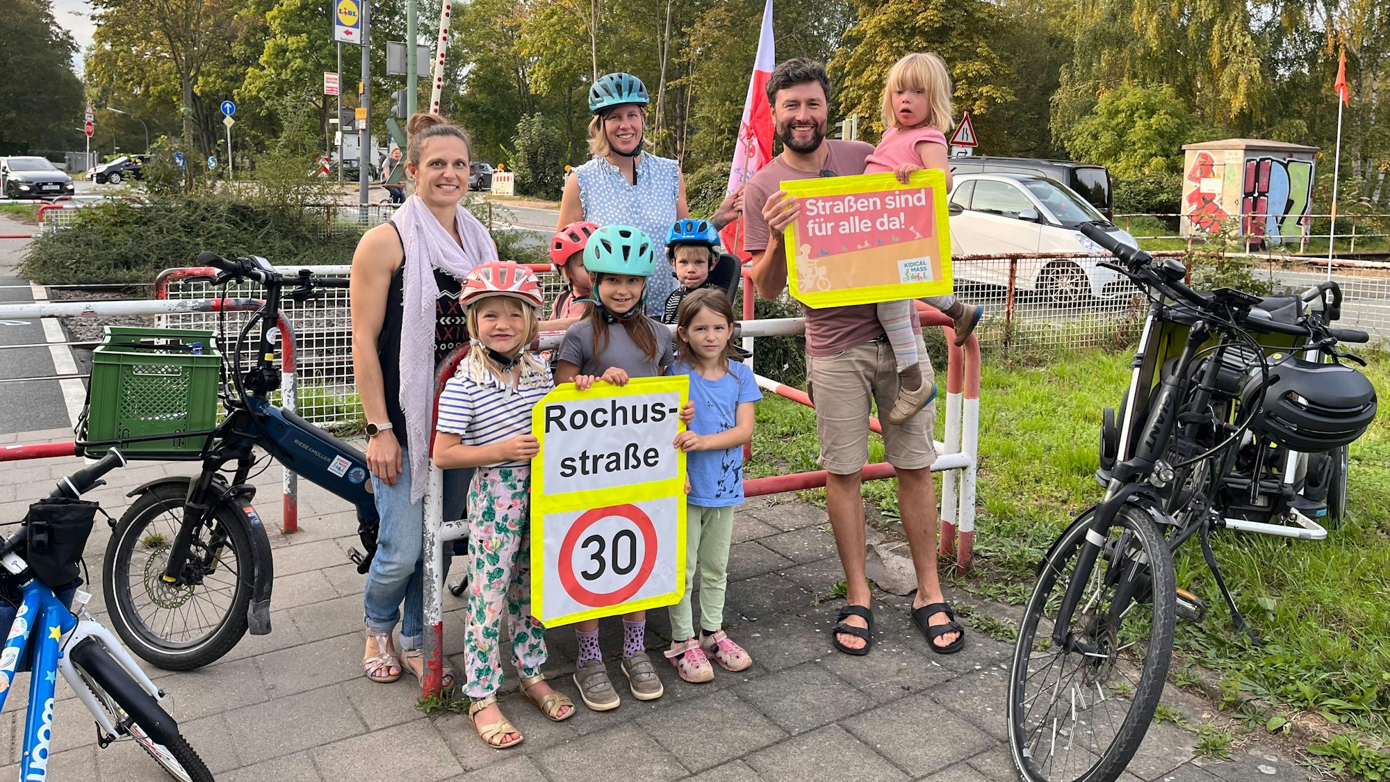 Eltern stehen vor einem Bahnübergang.