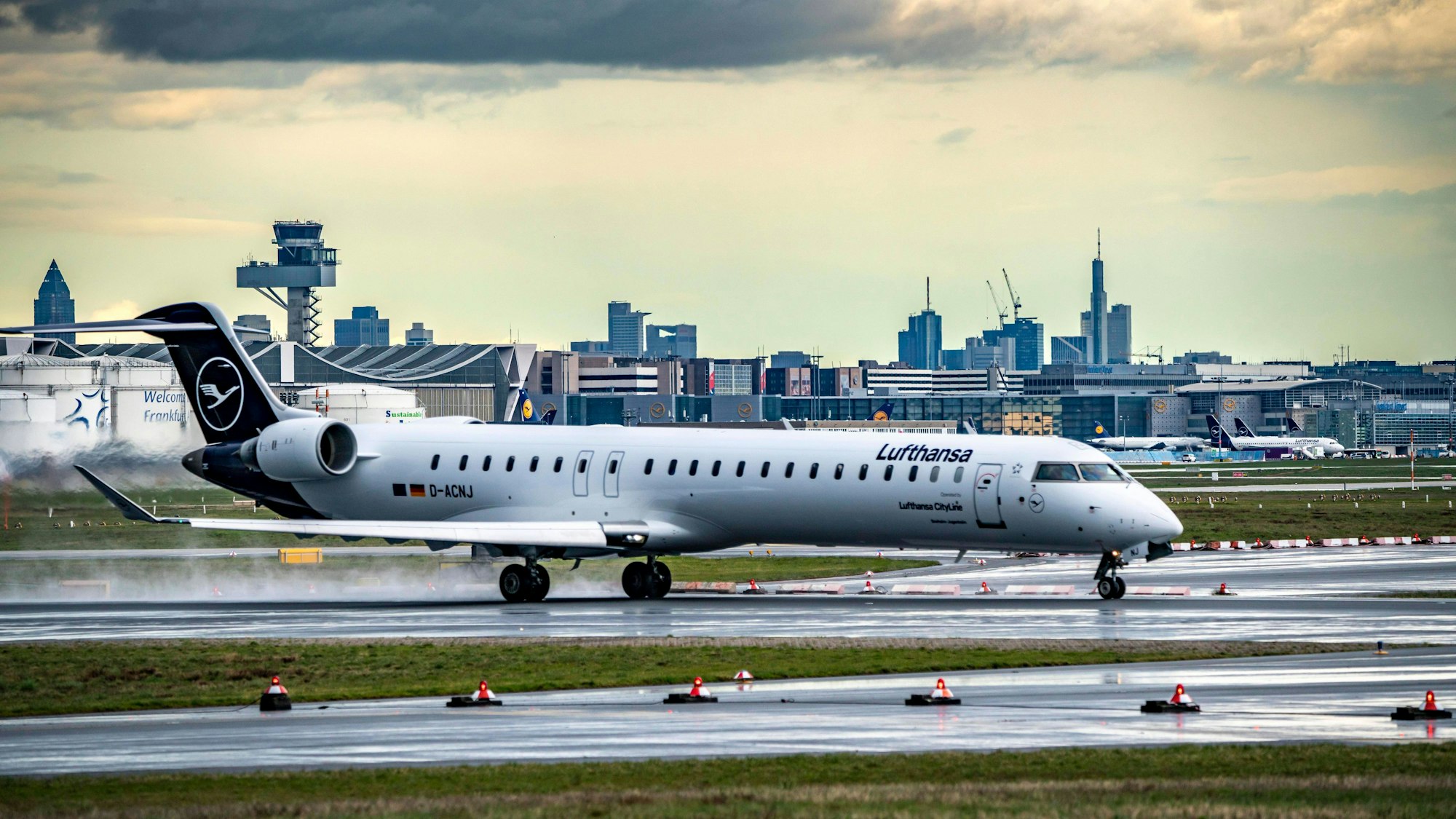 Ein CRJ-900 von Lufthansa startet auf der Startbahn West am Flughafen Frankfurt vor der Skyline der Innenstadt. (Symbolbild)