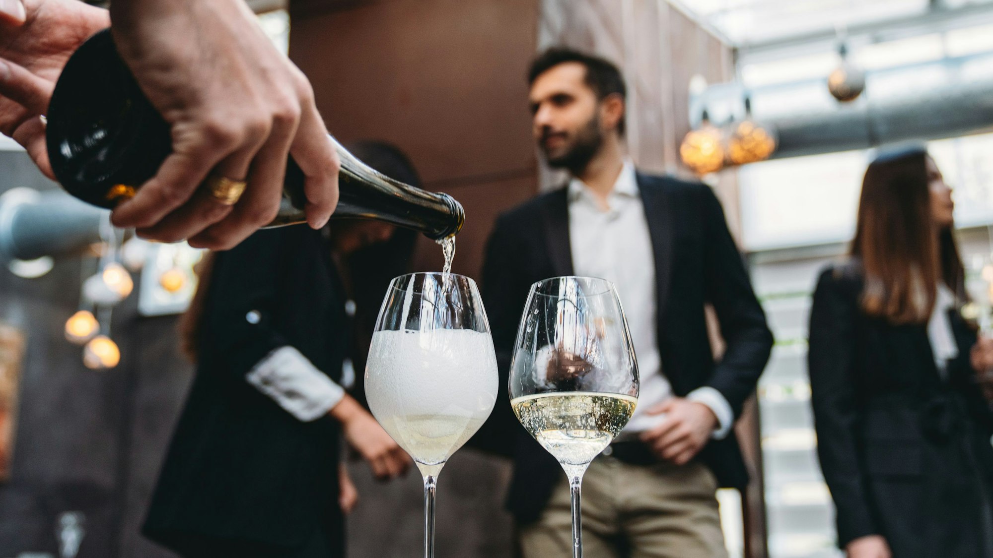 Kellner gießt in einem Restaurant Sekt in ein Glas