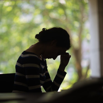 Eine Frau, von der man hauptsächlich die Silhouette erkennt, senkt den Kopf. (Symbolbild)